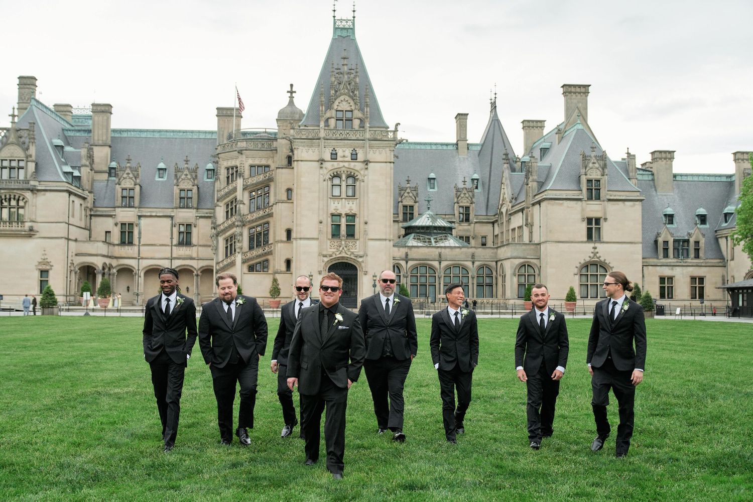 Group of people in formal attire walking across a manicured lawn at the Biltmore Estate in North Carolina.