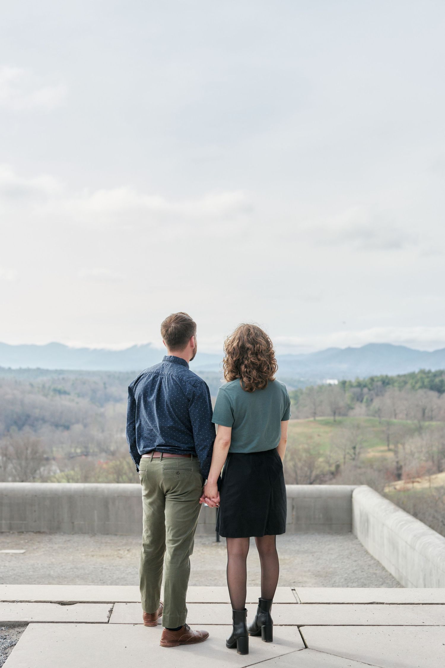 couple holding hand looking out into the mountains from the Biltmore Estate House.