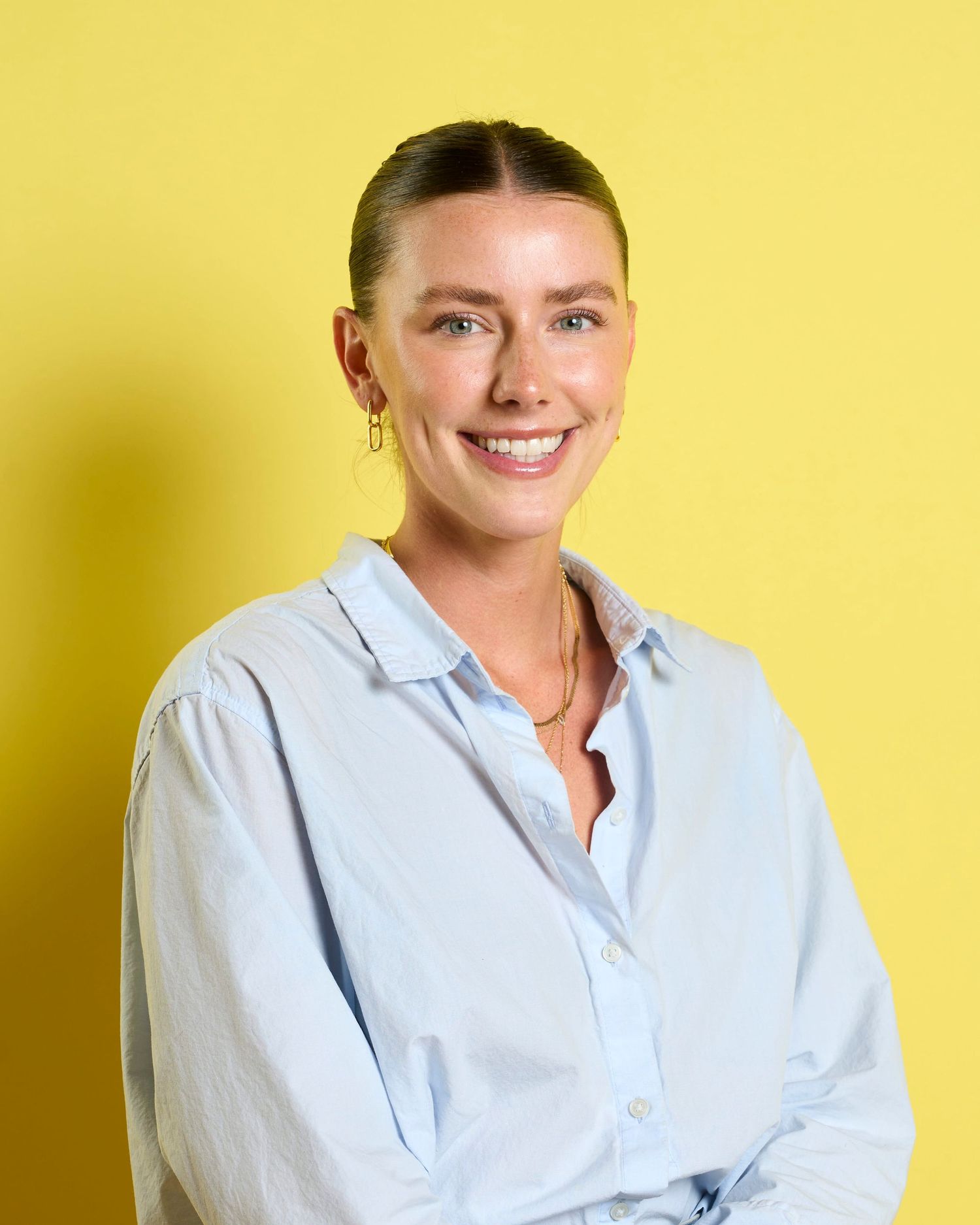 Professional business headshot of a lady siting in front of a yellow backdrop