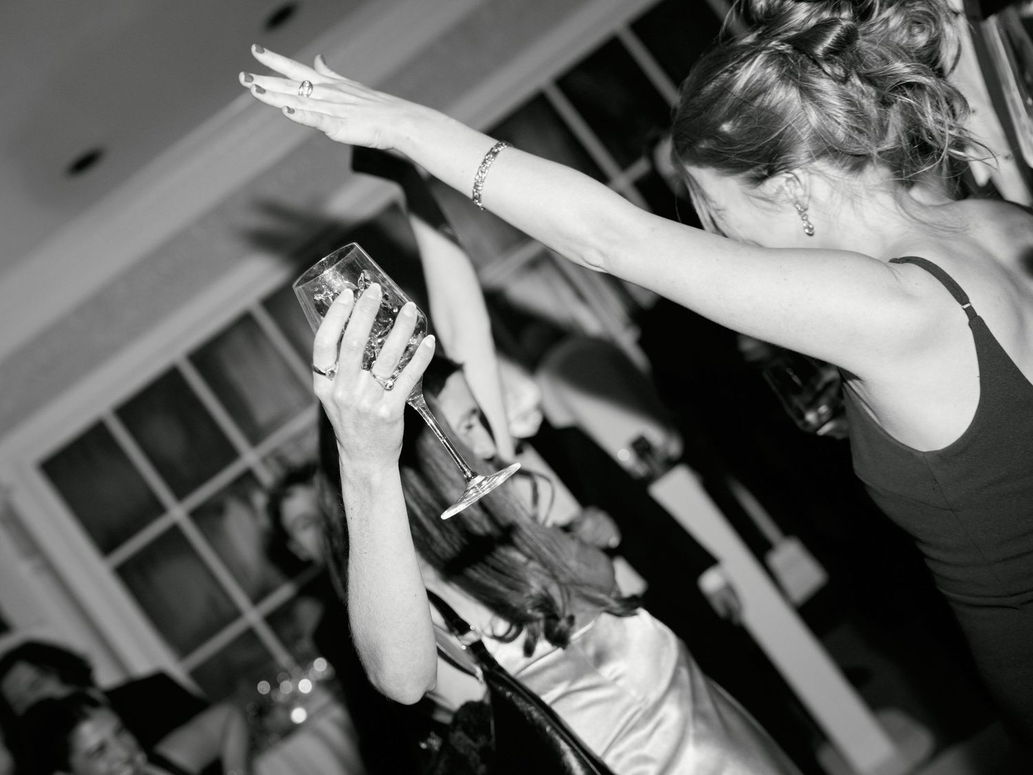 Black and white photo of women dancing and dabbing at a lively wedding reception party.