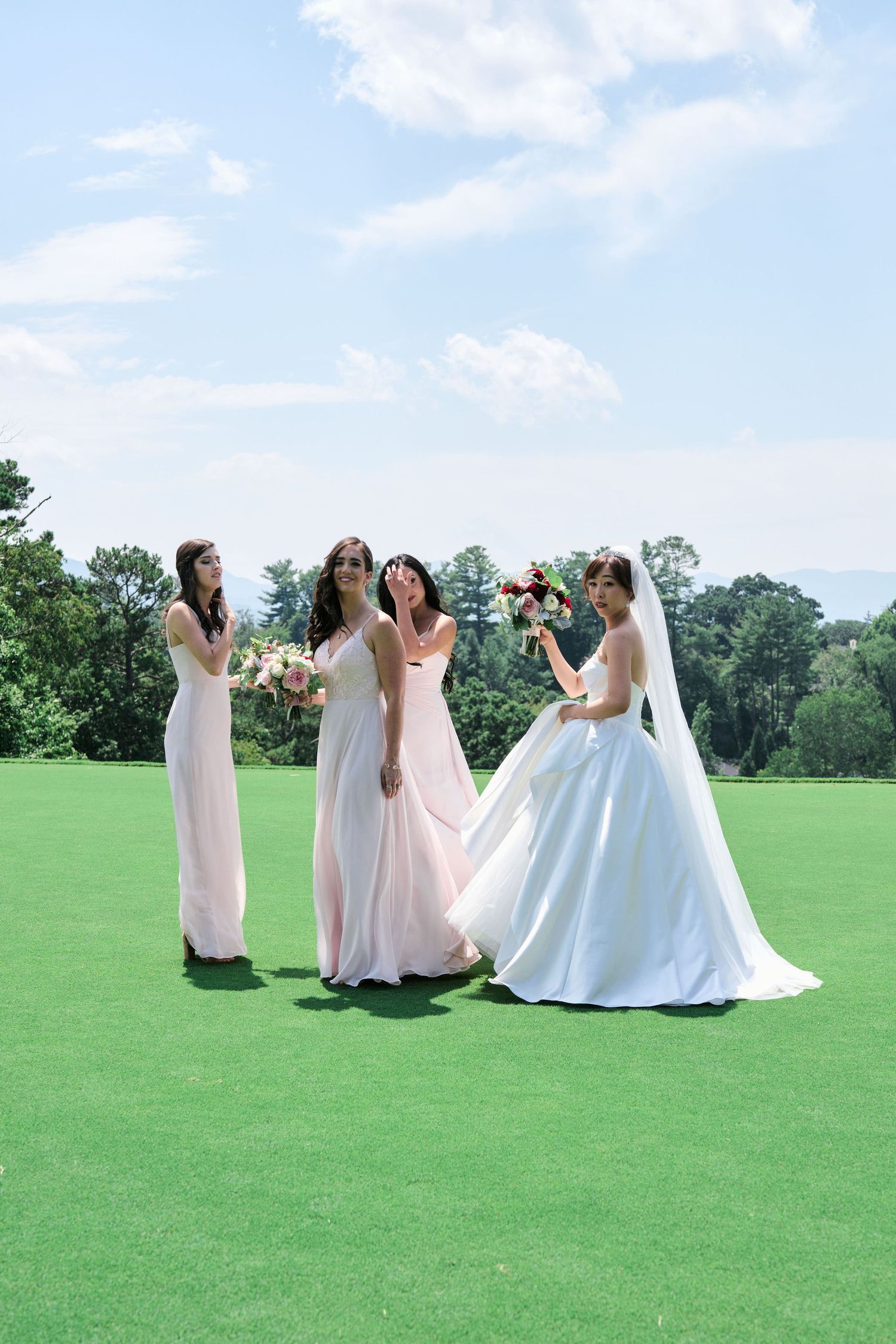 Wedding party in pink and white dresses shares joyful moments on a sunny golf course.