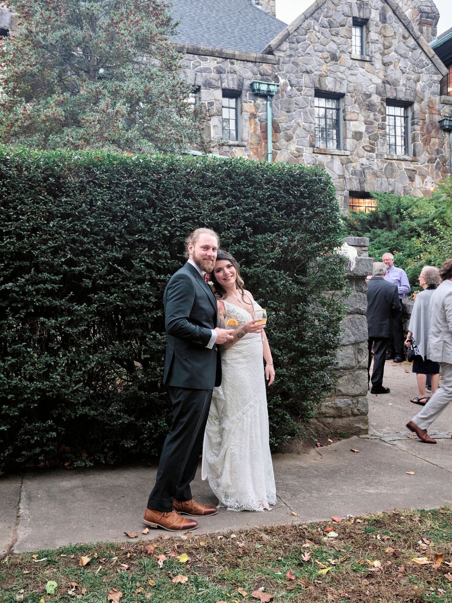 A couple embraces outside a stone castle building during their wedding celebration.