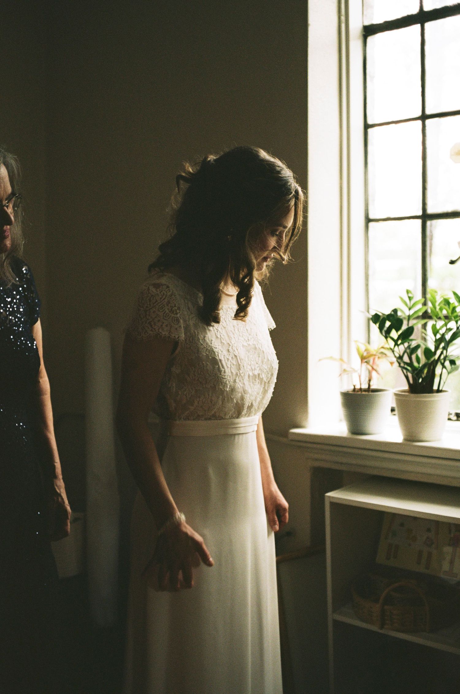 Natural window light illuminates a quiet moment in an elegant white dress.