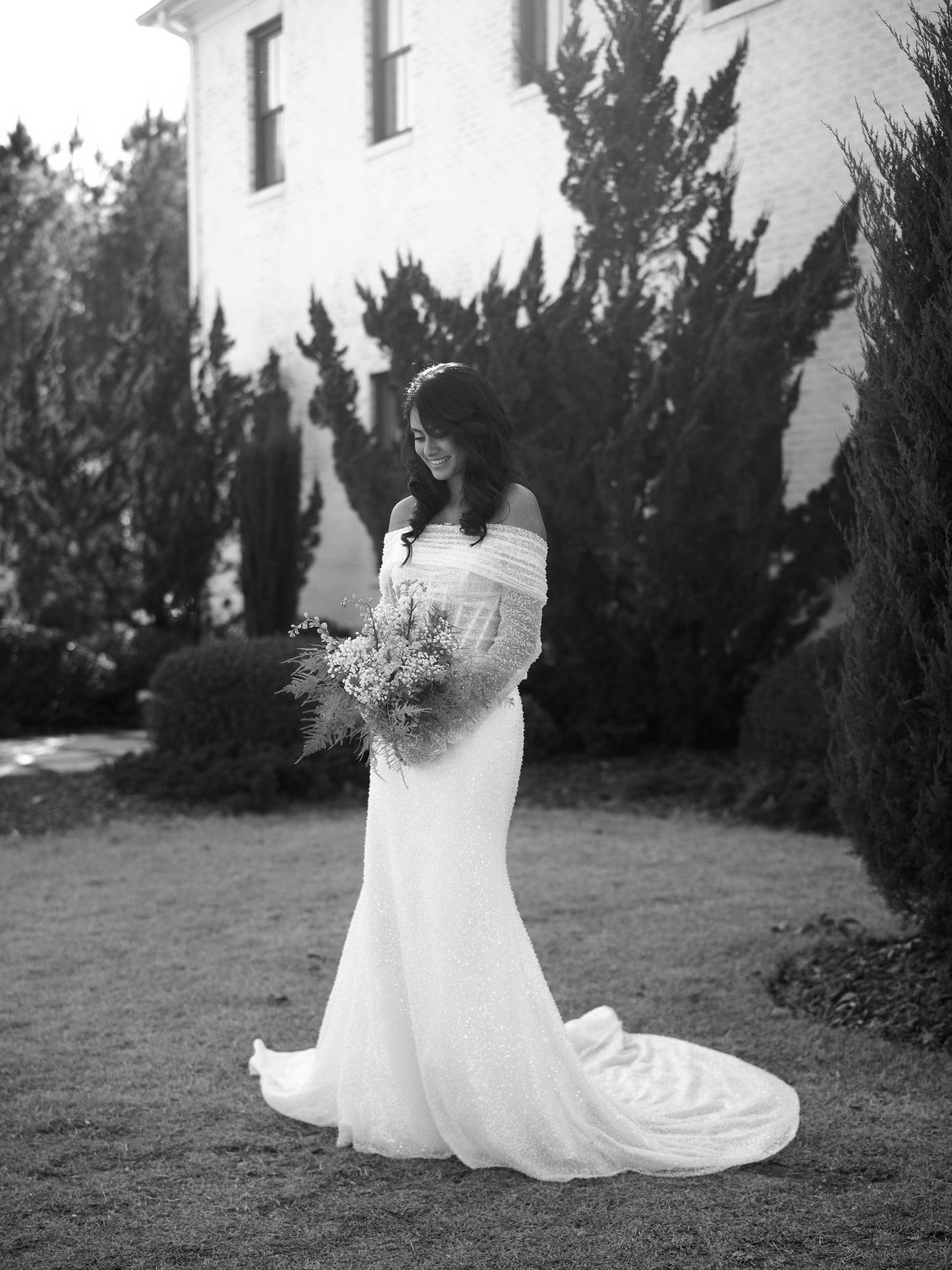 Bride smiling holding flowers in from of the Bradford venue in Raleigh, NC