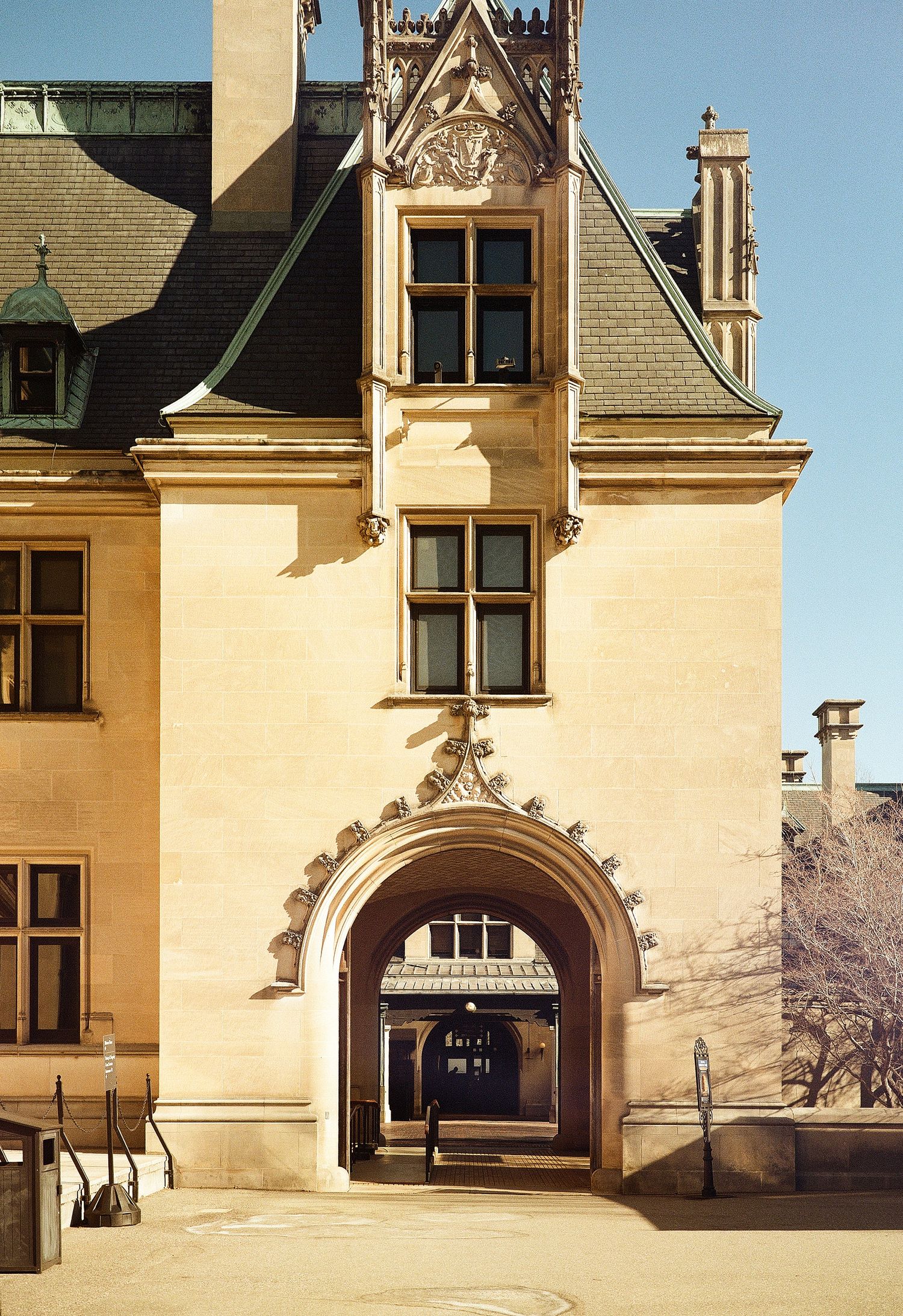 Gothic archway entrance of a cream-colored historic mansion with ornate architectural details and pointed dormer window.