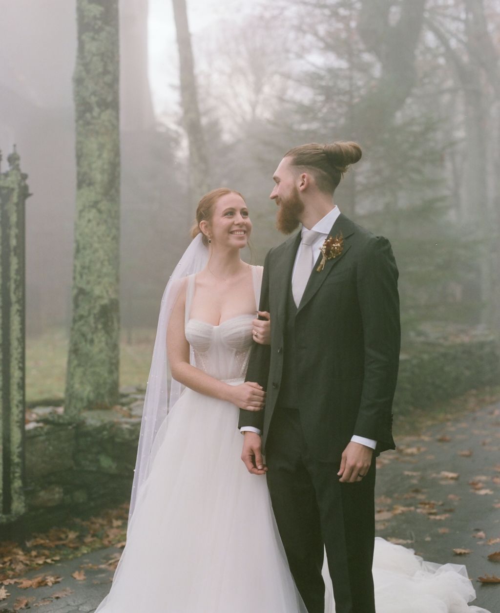 A romantic autumn wedding portrait in a misty forest setting.