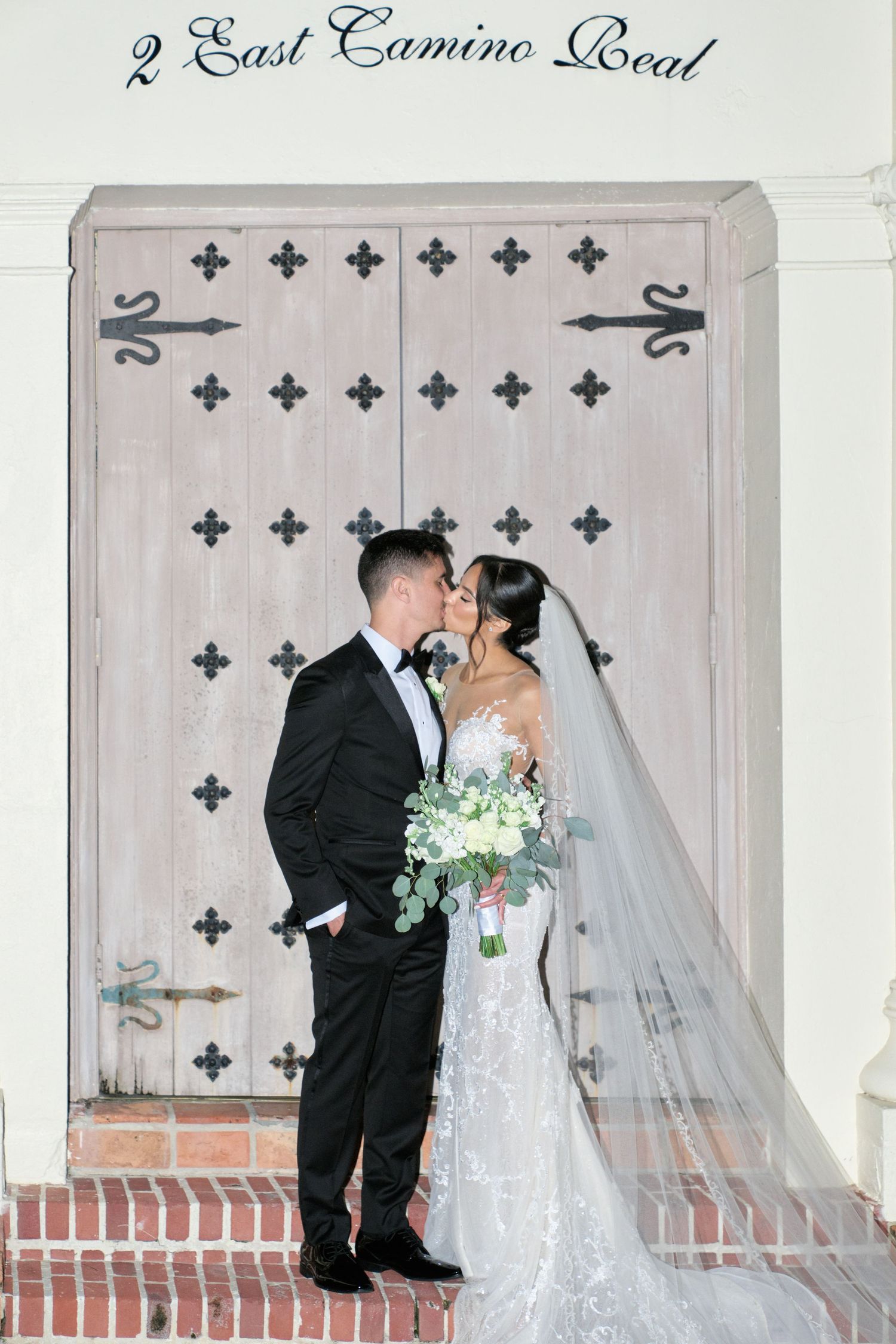 Newlyweds pose in front of decorative door at 2 East Camino Real.