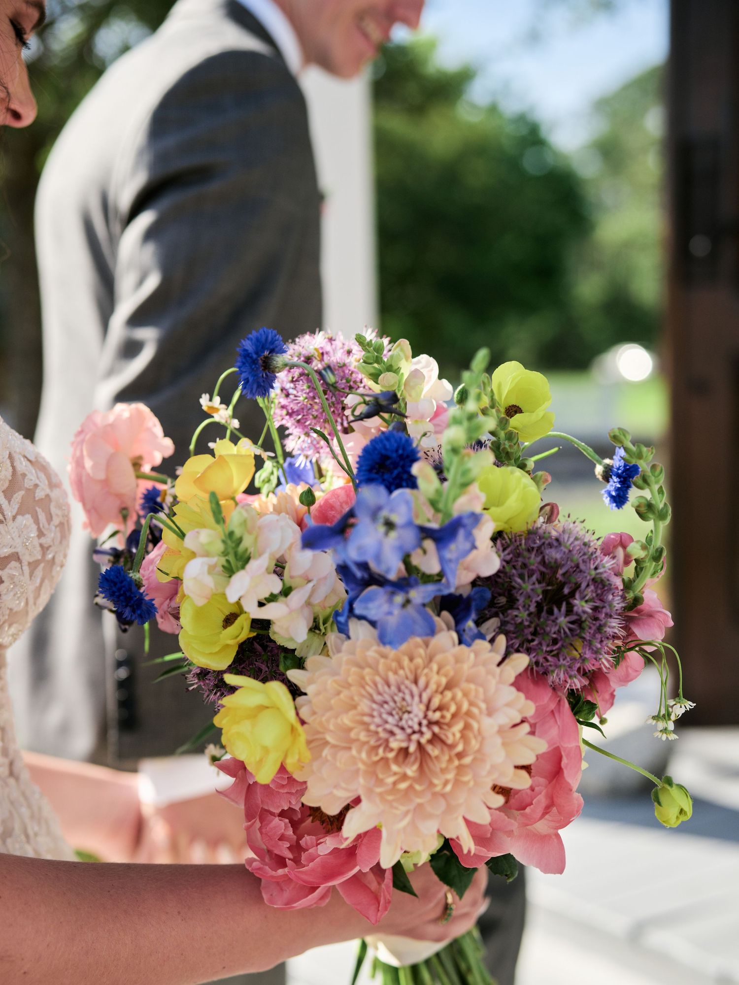Vibrant wedding bouquet with yellow orchids, blue delphiniums, and pink dahlias.