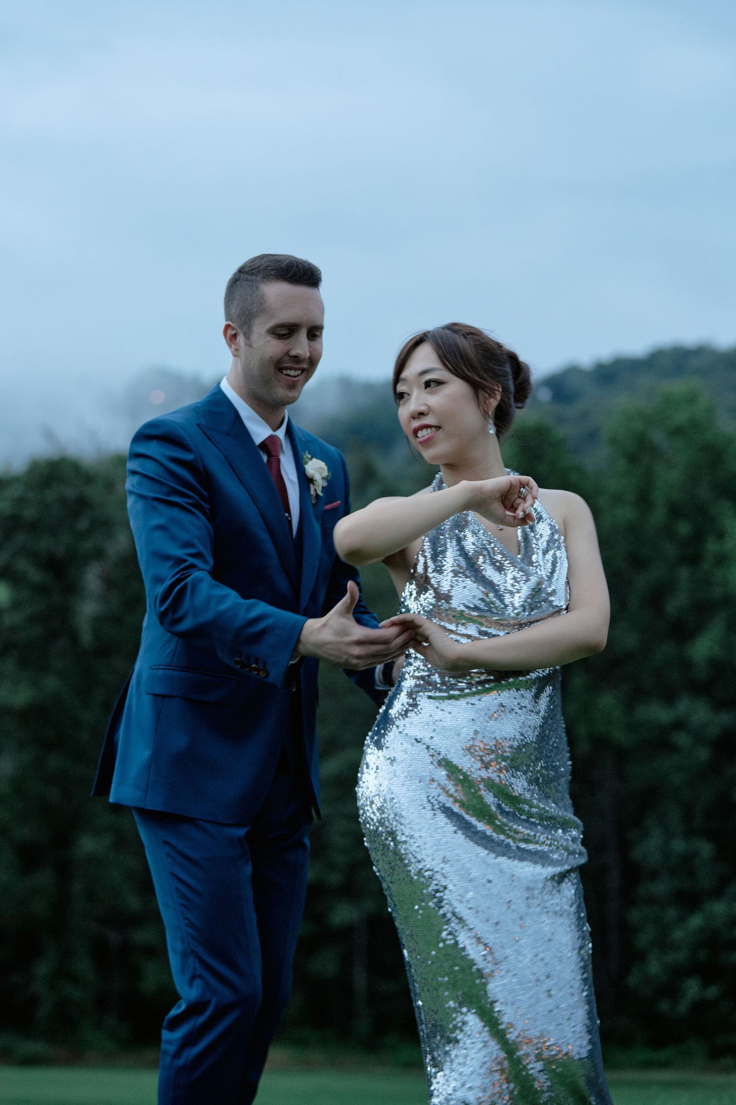 A couple dances together on a golf course at dusk, with the bride in a silver sequined gown.