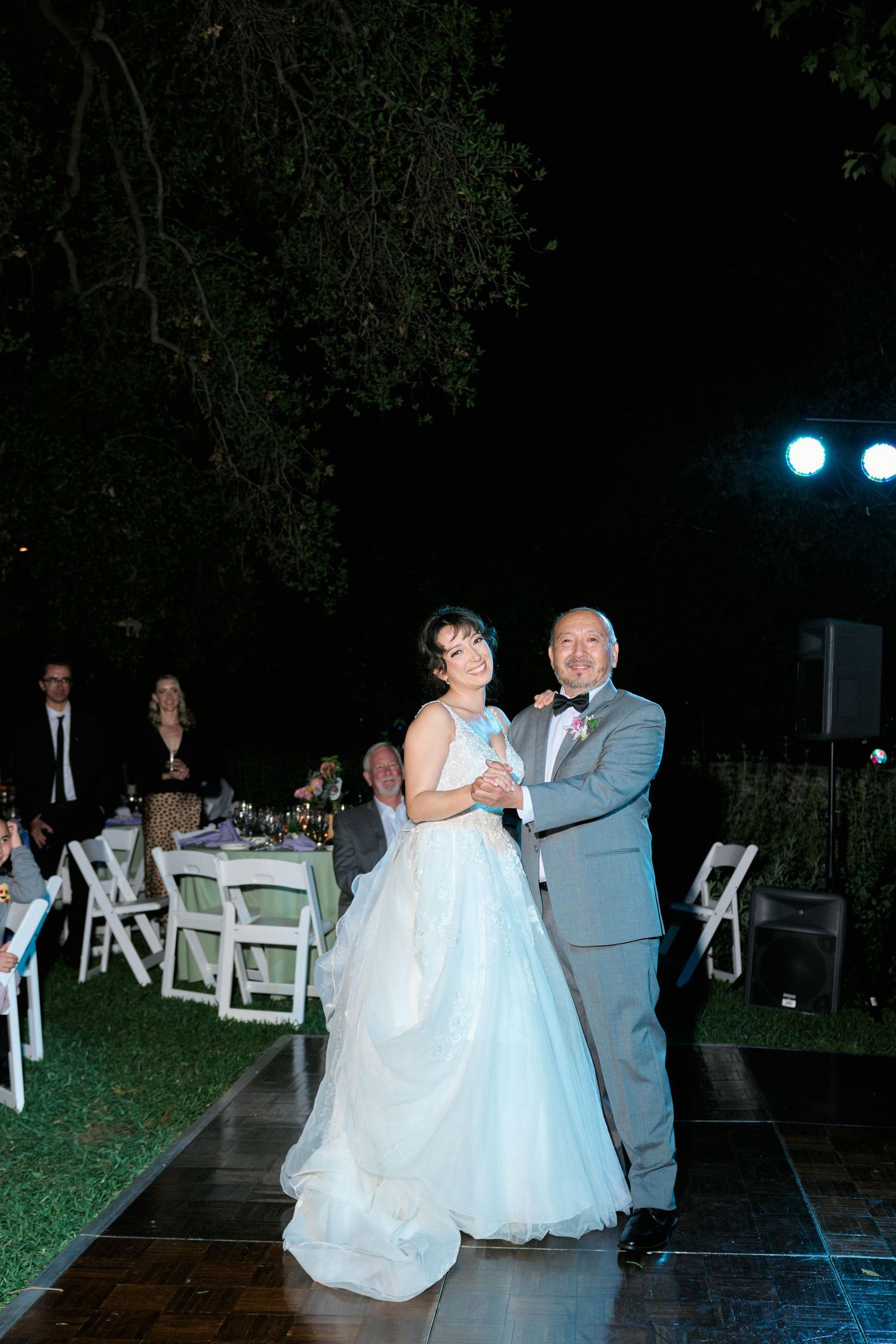 Couple sharing tender dance moment on outdoor wooden dance floor at night.