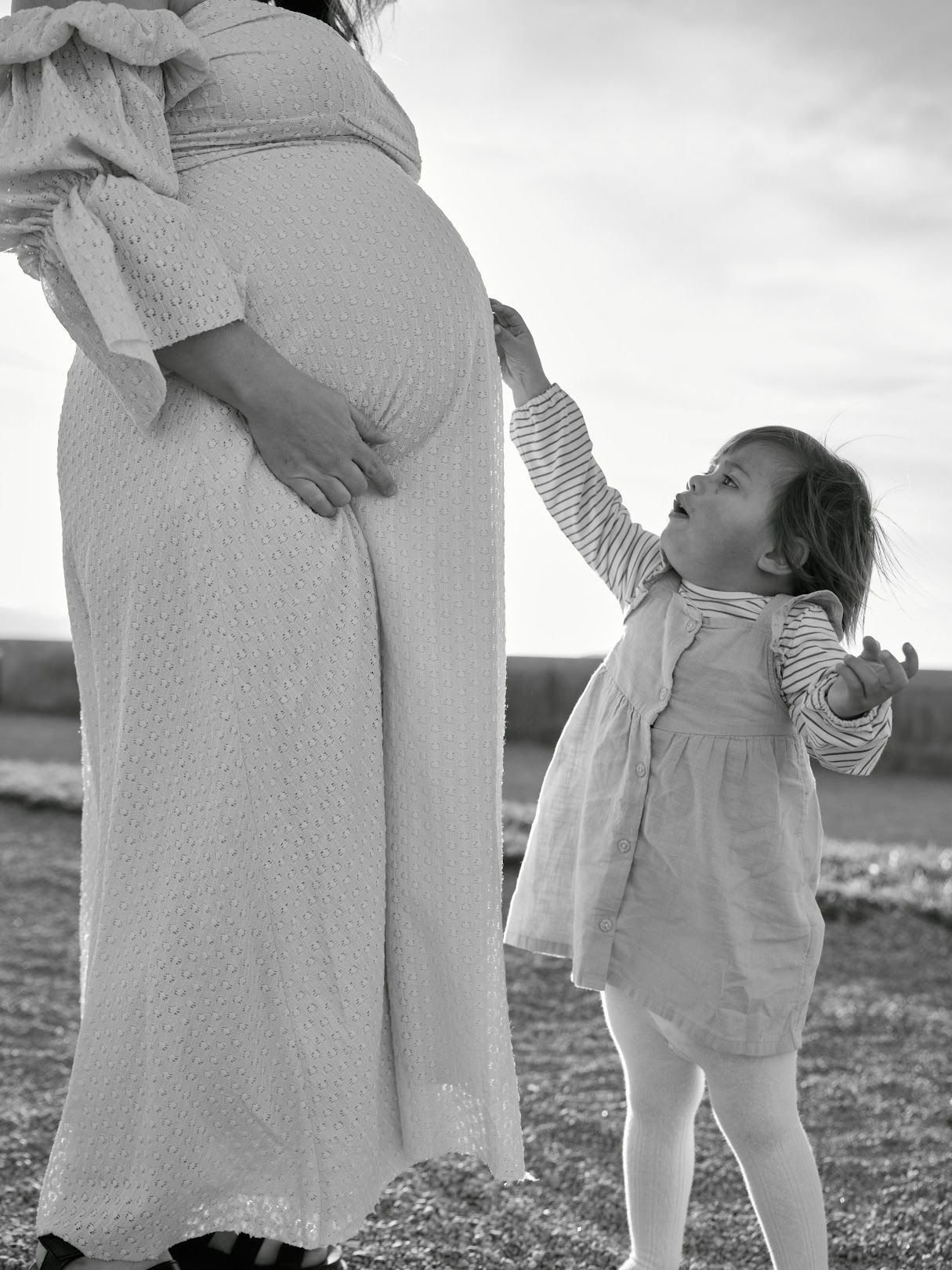 A black and white series of images showing a small child hugging and interacting with someone in light colored clothing.