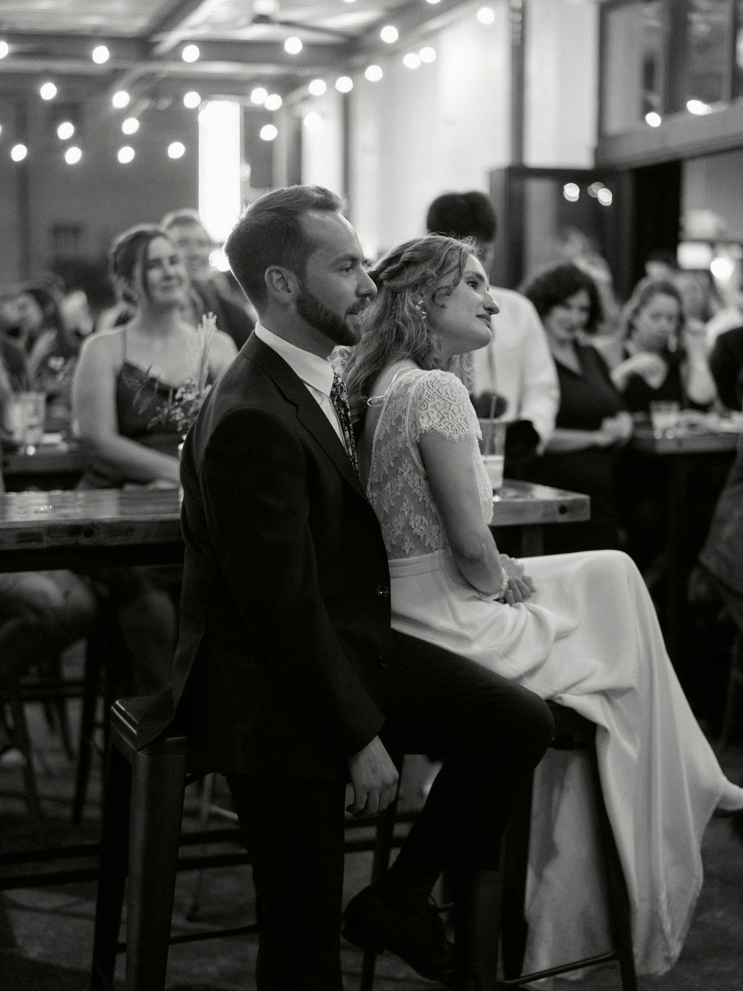 A couple shares an intimate moment at their wedding reception with string lights glowing in the background.