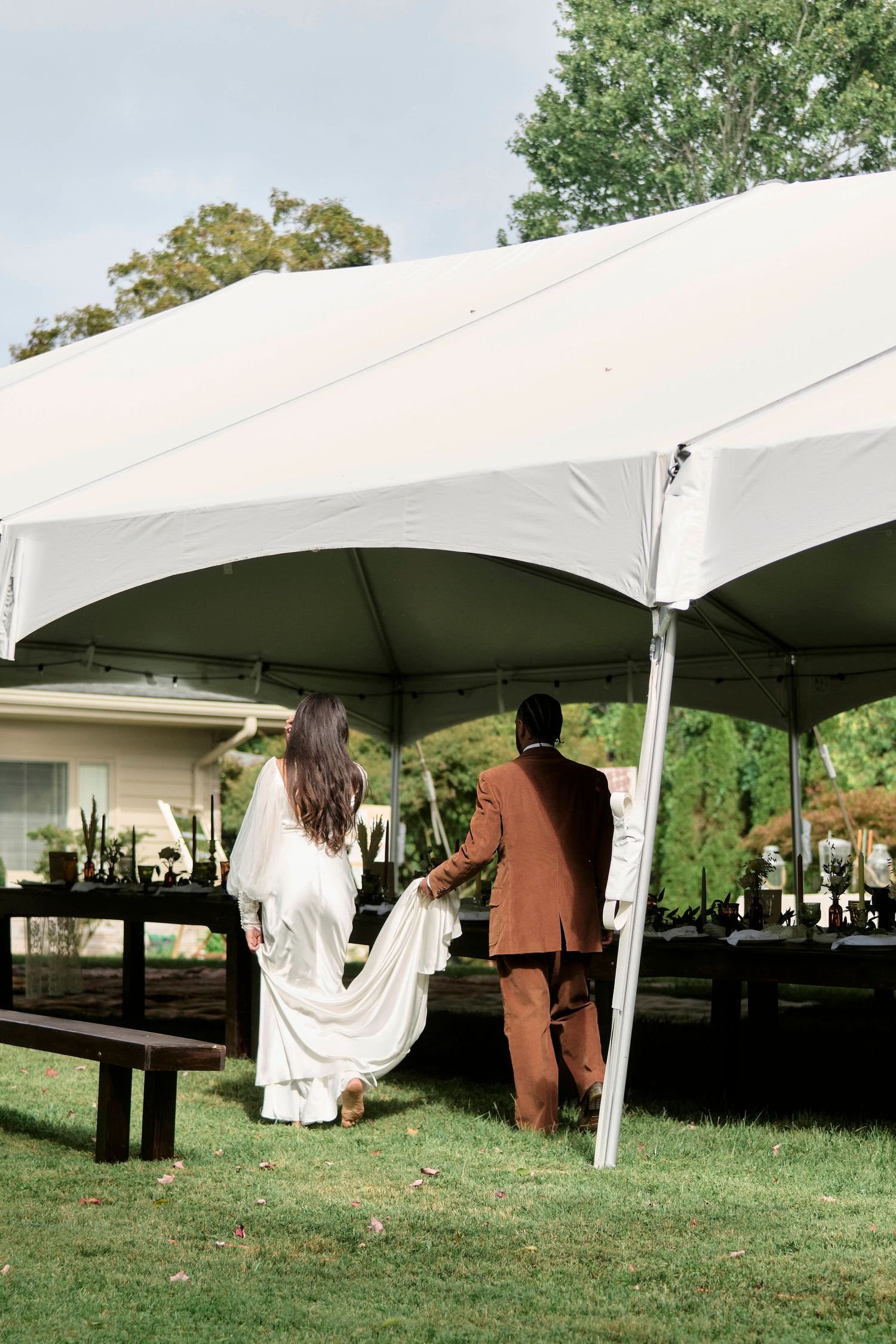 bride and groom walking under their alfresco style wedding reception.