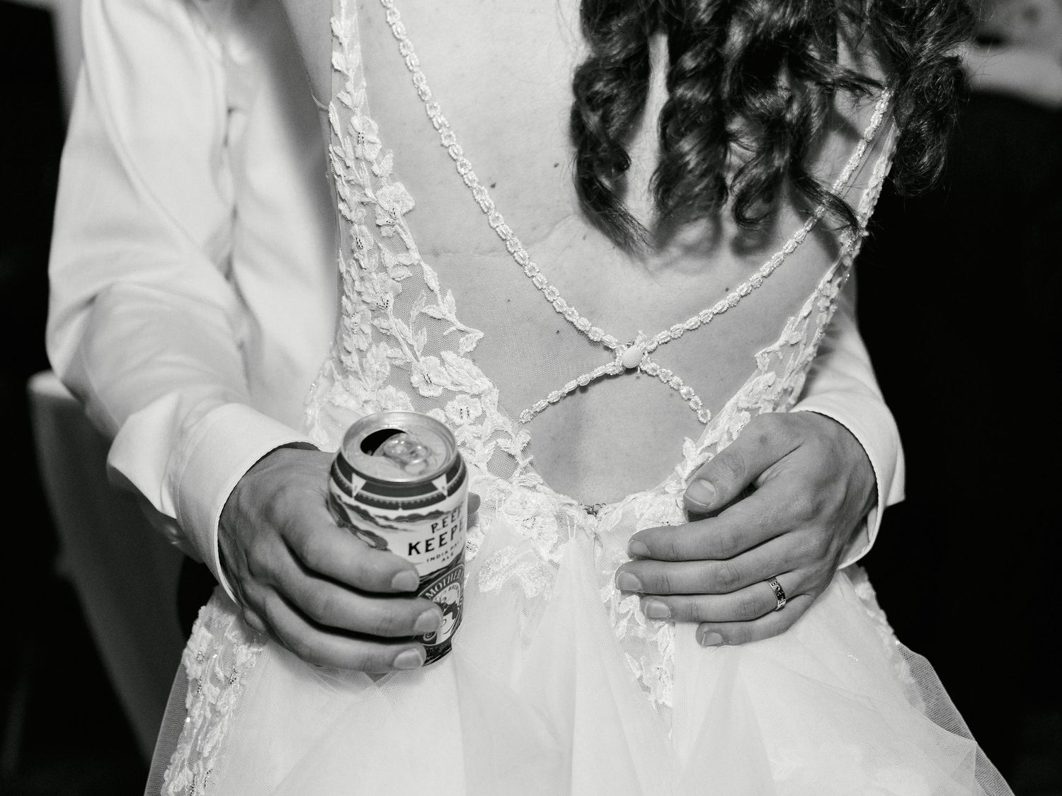 Black and white photo showing hands holding a Pepsi can against a white lace wedding dress.