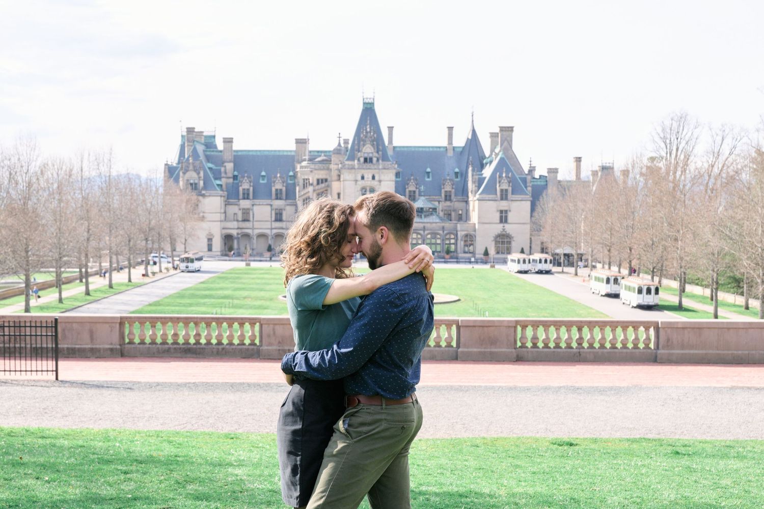 A romantic couple sharing a tender moment in front of the grand Biltmore Estate mansion.