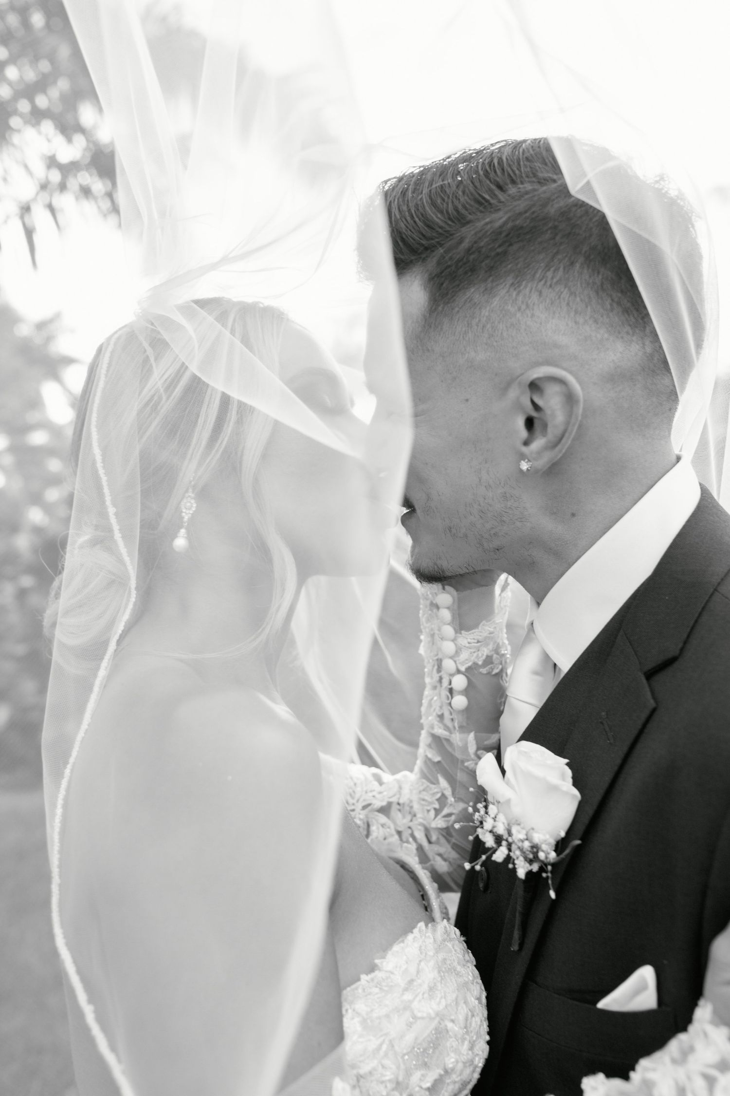 Intimate black and white wedding portrait through delicate veil fabric.