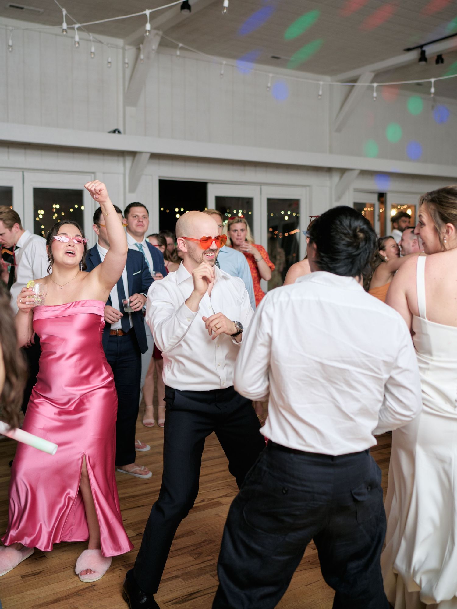 Wedding reception dance party with colorful lights and energetic guests on the dance floor.