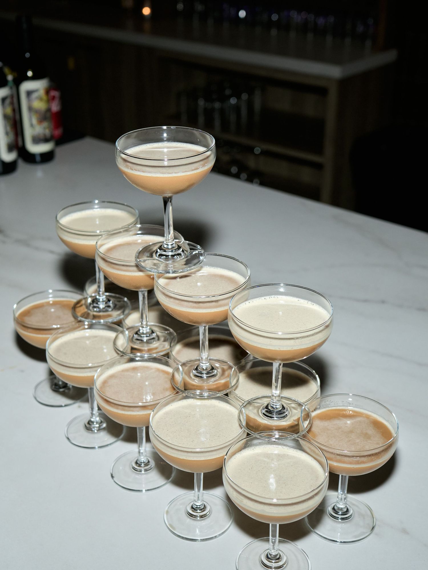 Four coupe glasses filled with espresso martinis arranged on a white marble countertop.