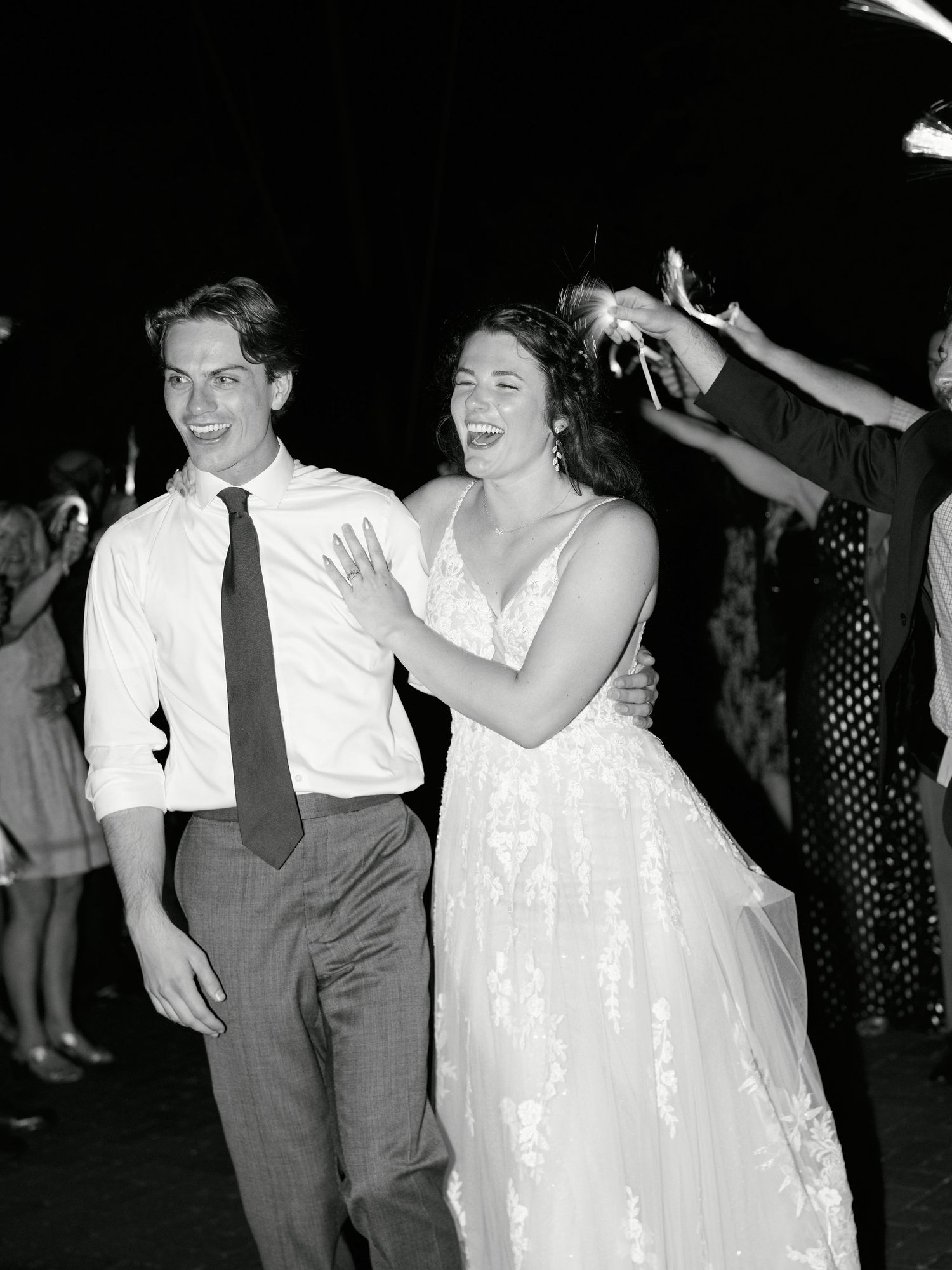 A couple dancing together at a celebration, the bride wearing a white gown and her partner in a shirt and tie.