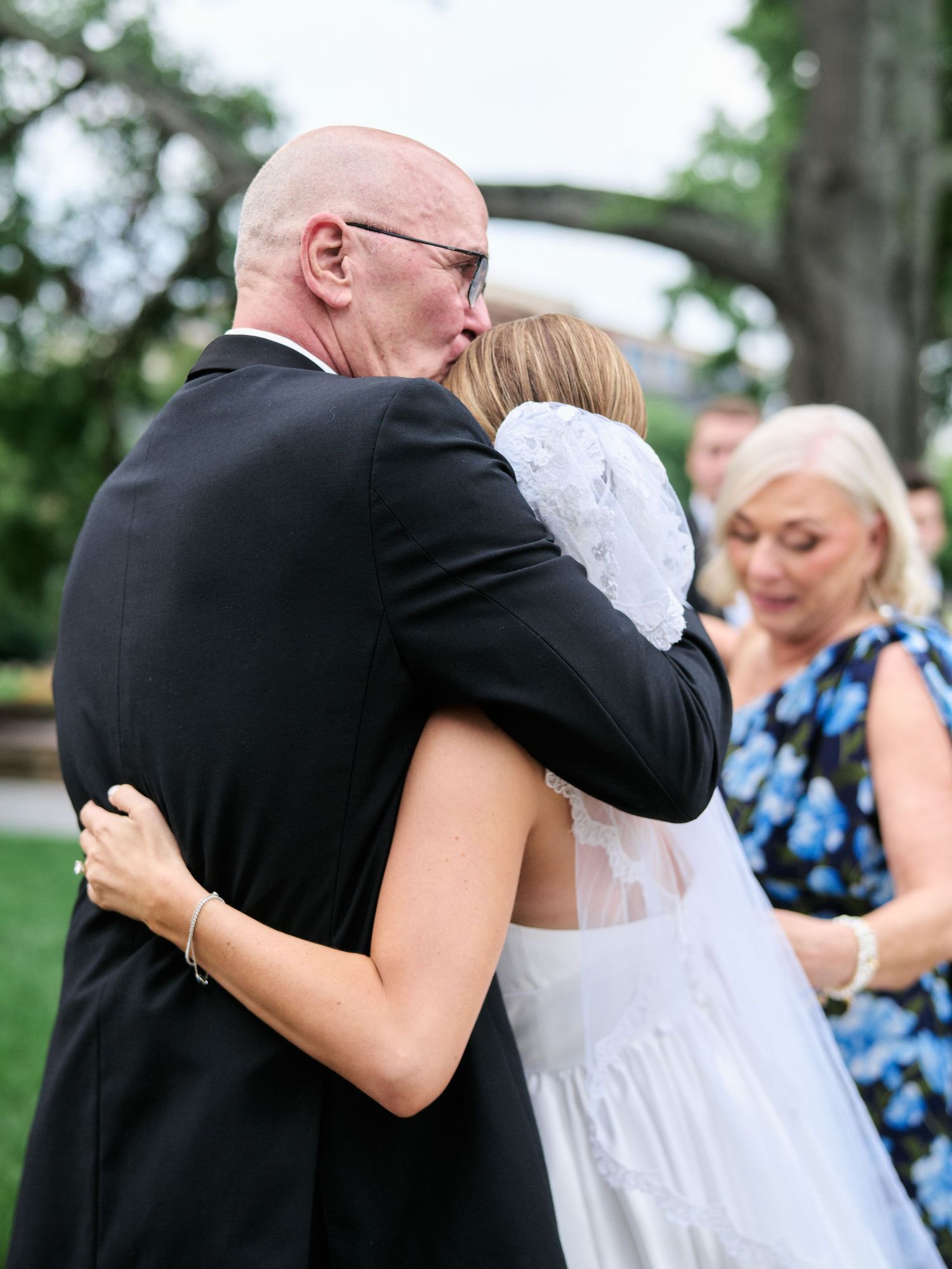 Emotional embrace during outdoor wedding ceremony with floral decorations.