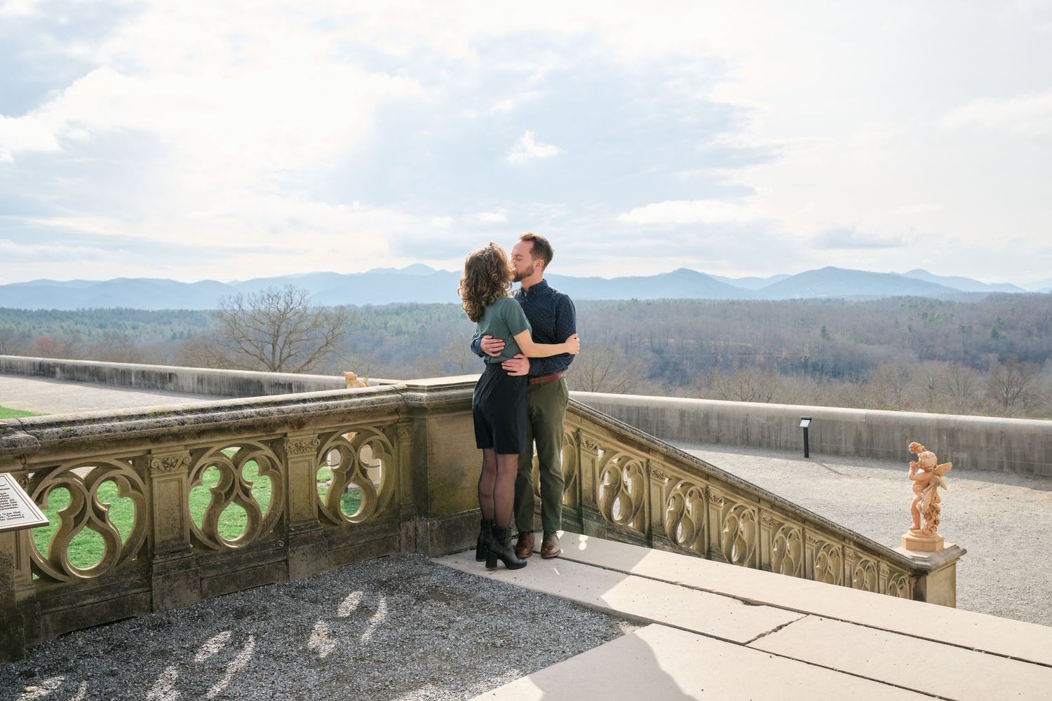 Couple sharing an intimate moment on a mountain viewpoint overlooking a scenic valley.