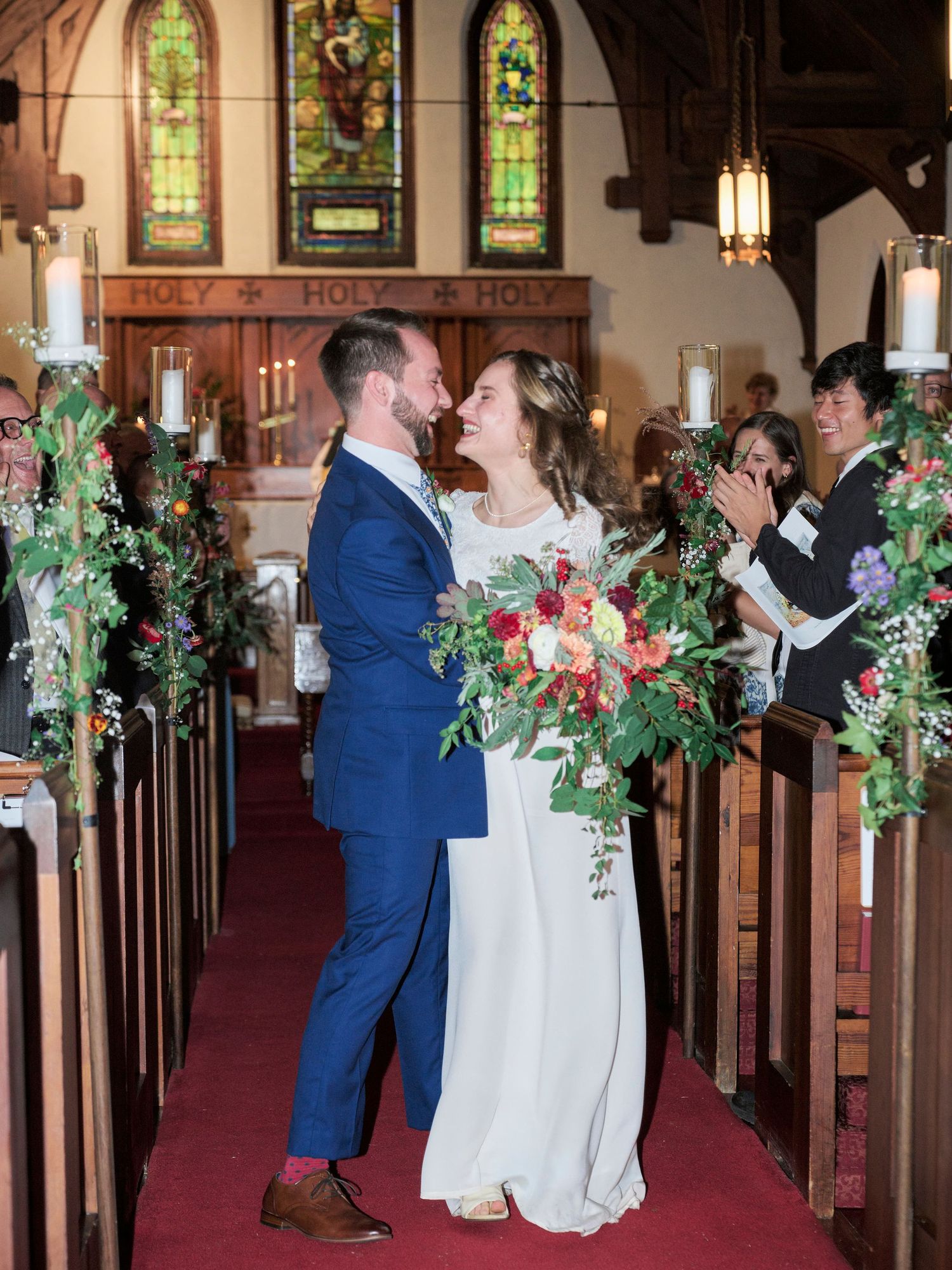 A romantic moment between newlyweds in a church aisle decorated with greenery and candles.