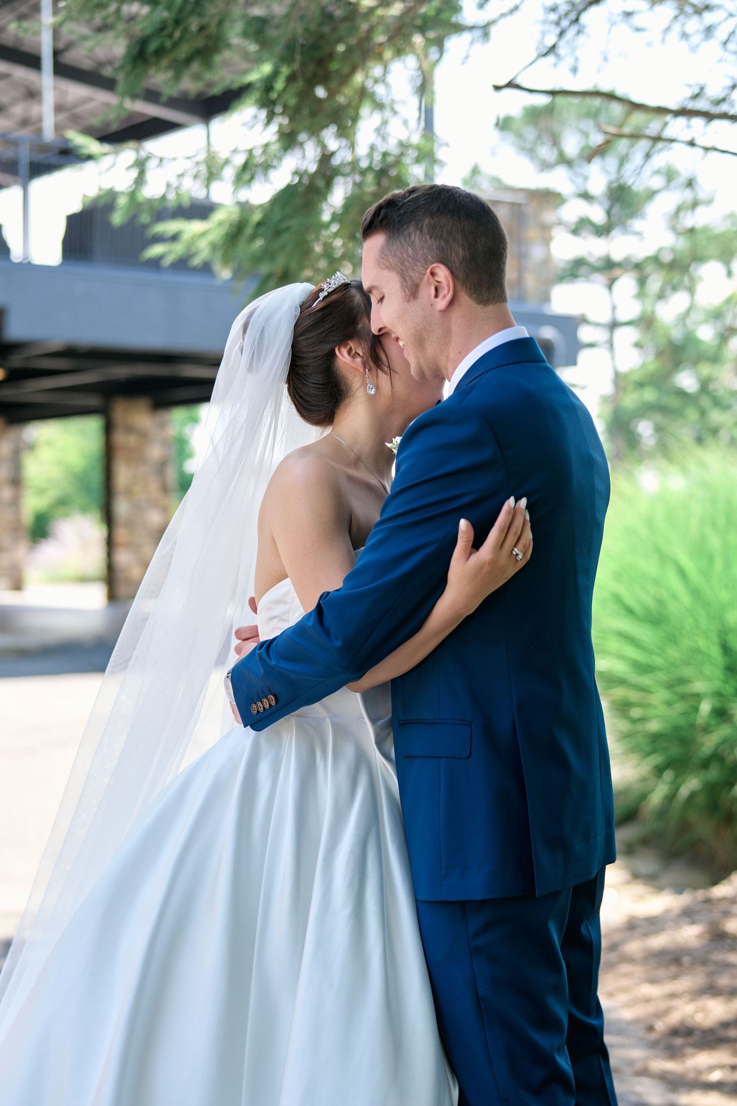 A tender kiss between newlyweds on their wedding day in an outdoor garden setting.