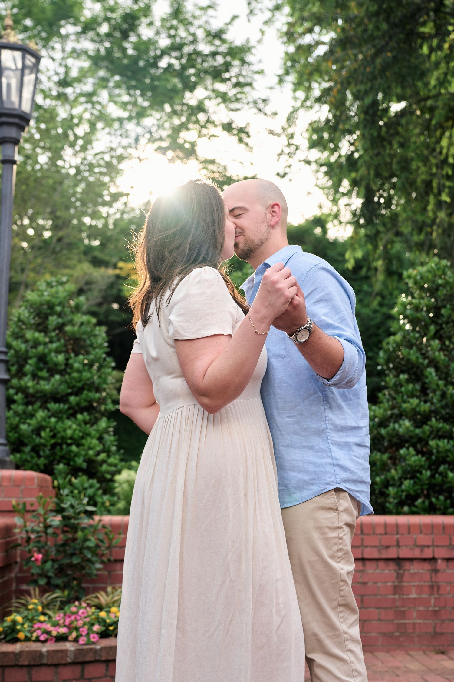 A couple dancing together in formal wear on a brick patio at sunset.