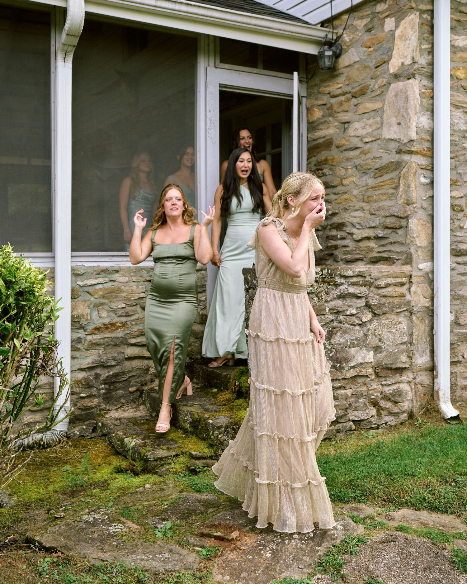 A sequence of photos showing a person in a flowing beige dress peeking and posing around a stone wall corner.