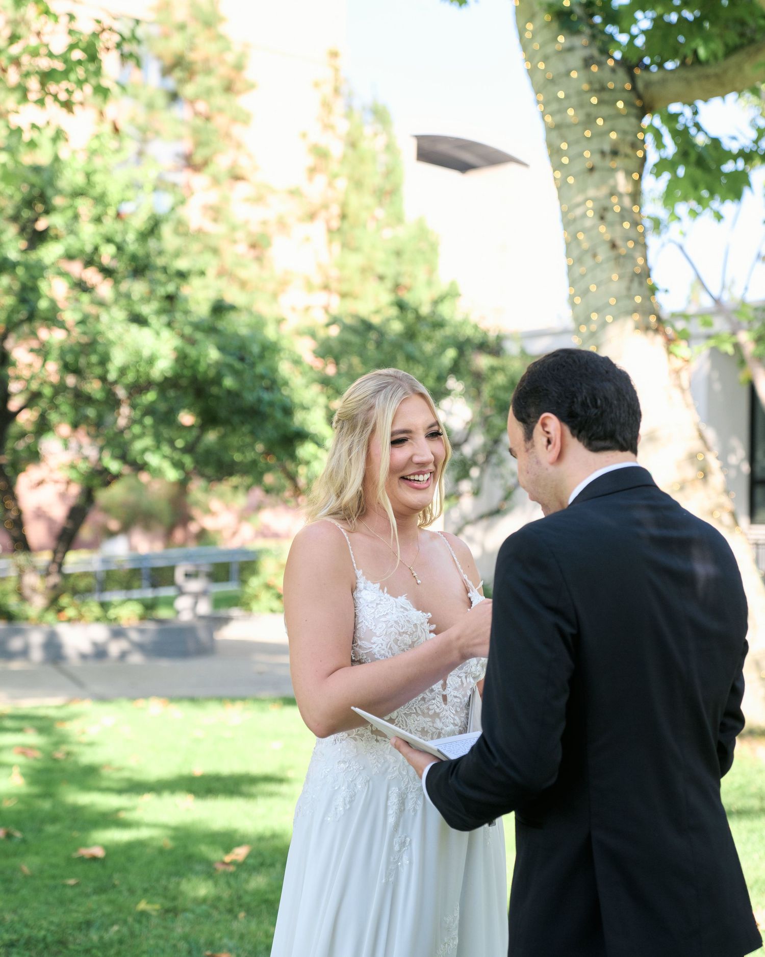 A joyful moment captured during an outdoor wedding ceremony under green trees.