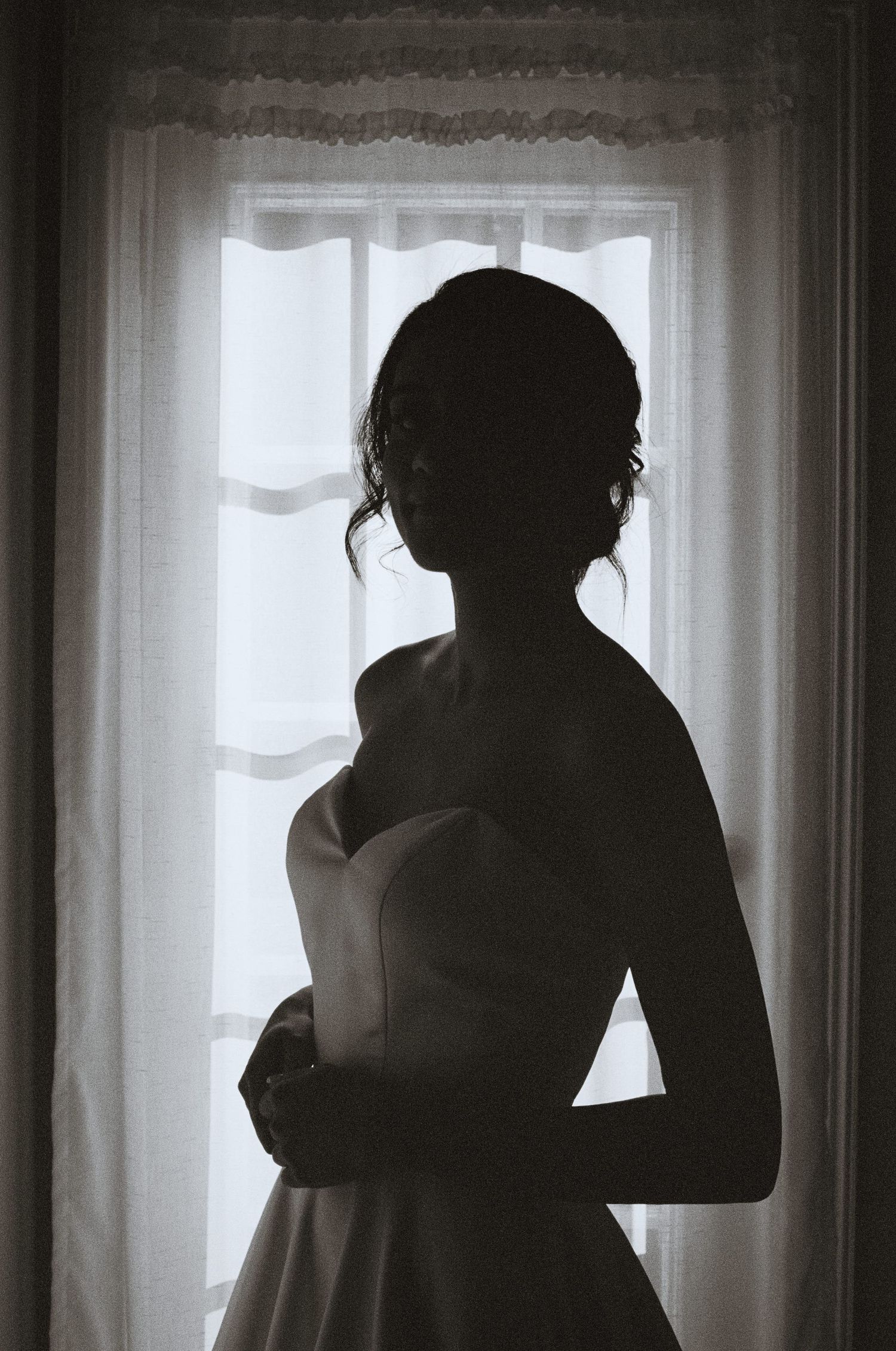 bride standing in front of a window as she's getting ready at the Bradford