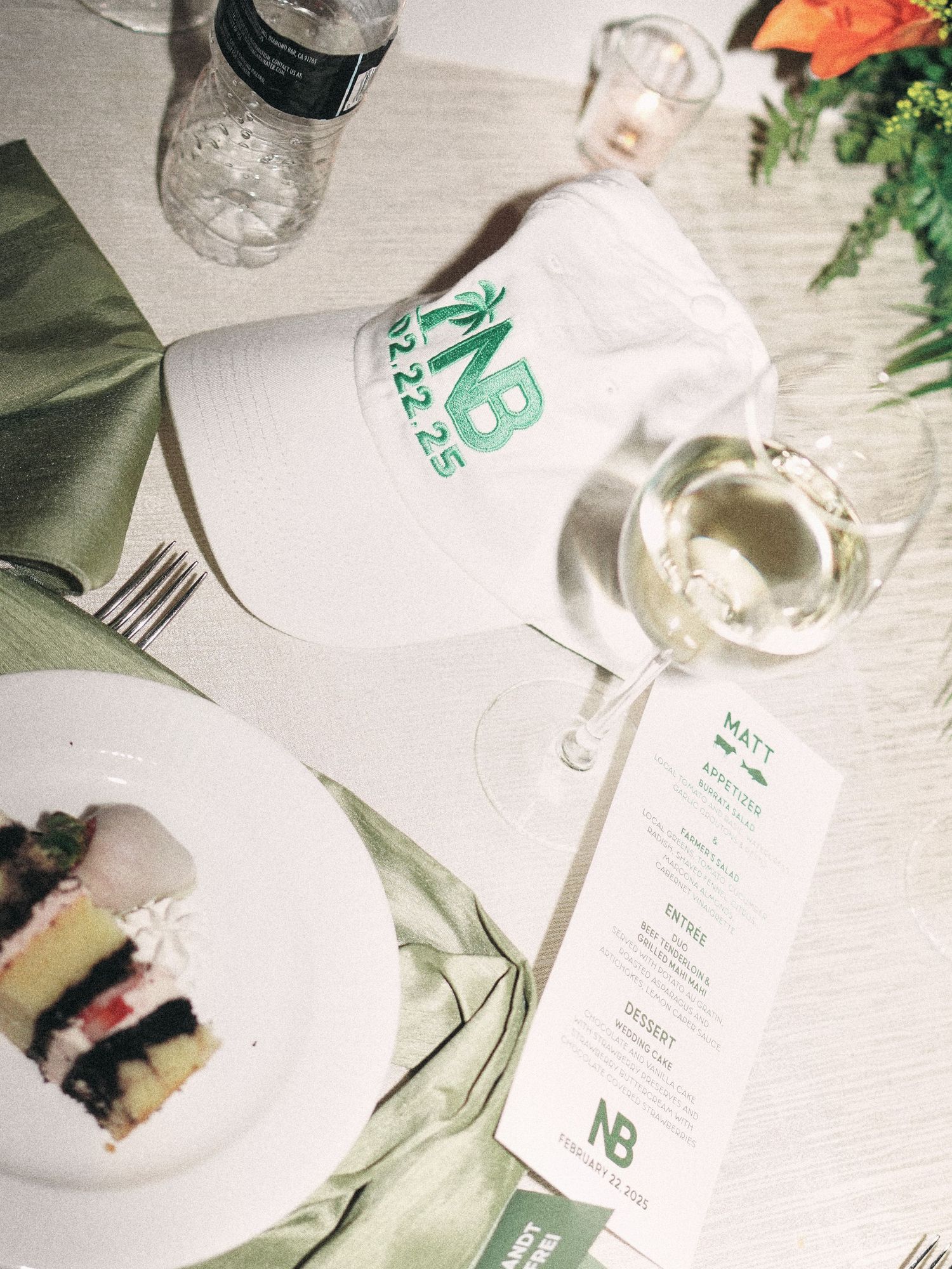 Elegant table setting with a white baseball cap, wine glass, menu card and dessert plate in natural lighting.