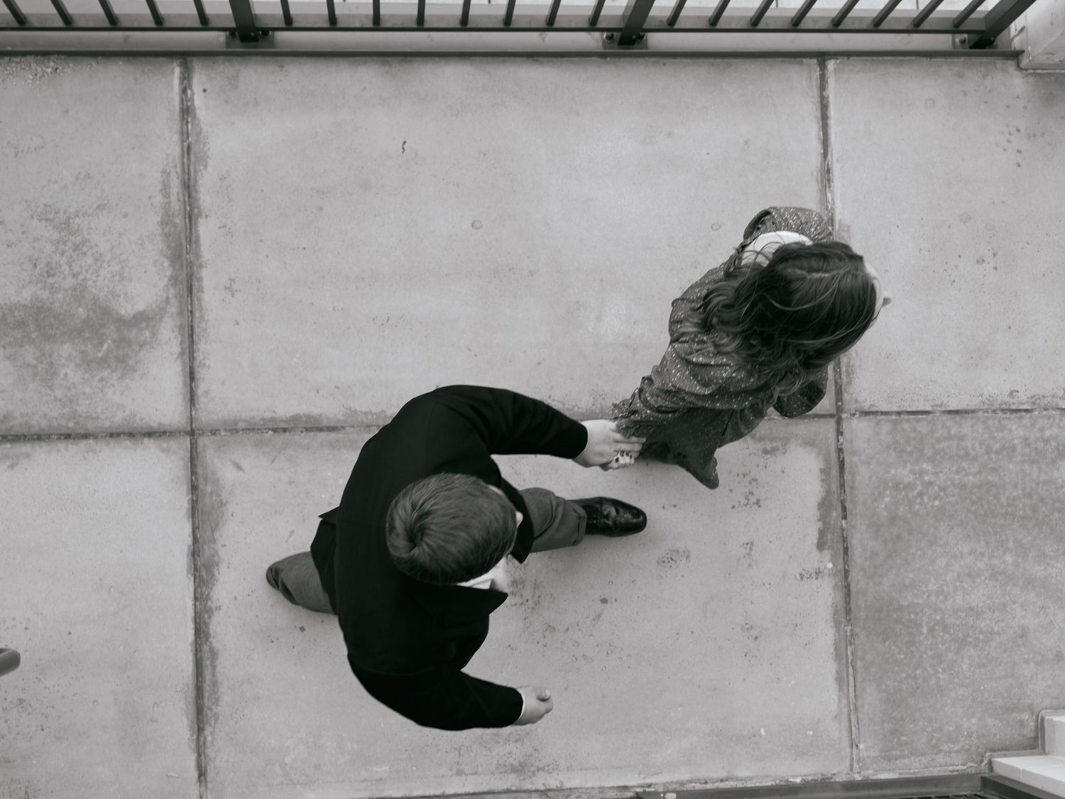 A black and white aerial view of two people dancing on a concrete surface.