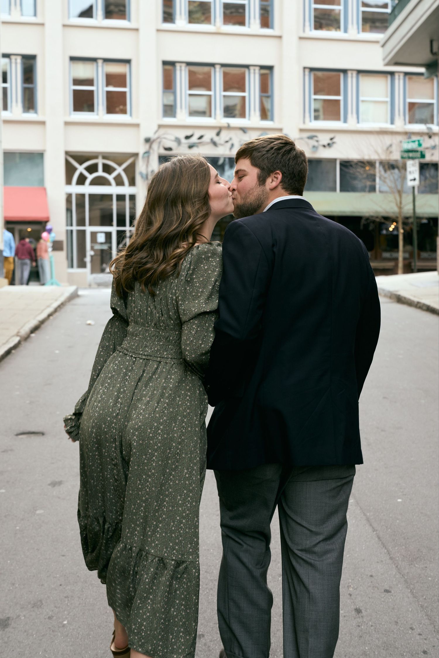 A romantic couple shares a tender moment on a city street corner.