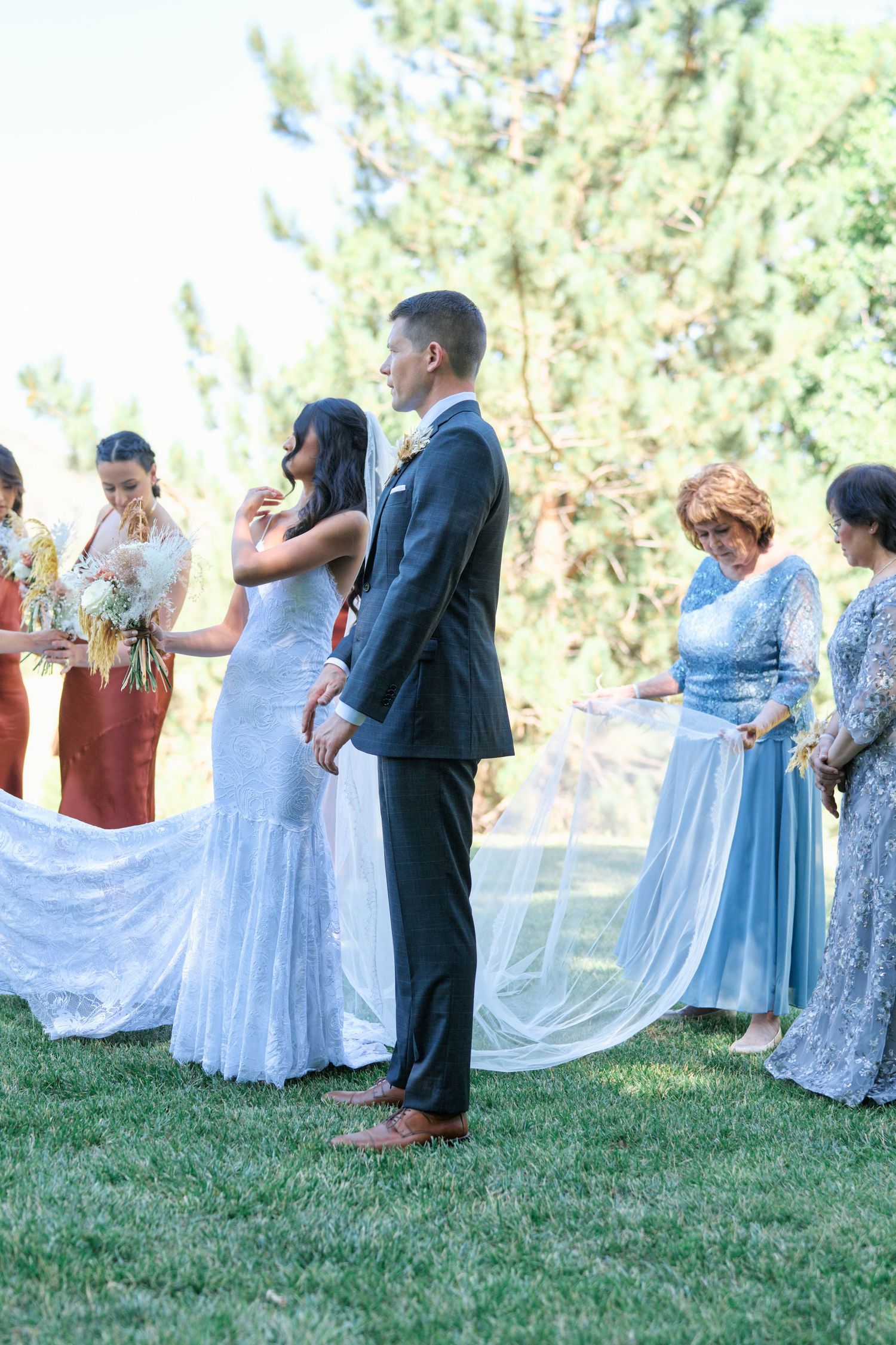 An outdoor wedding ceremony with attendees in formal attire gathered on a lawn.