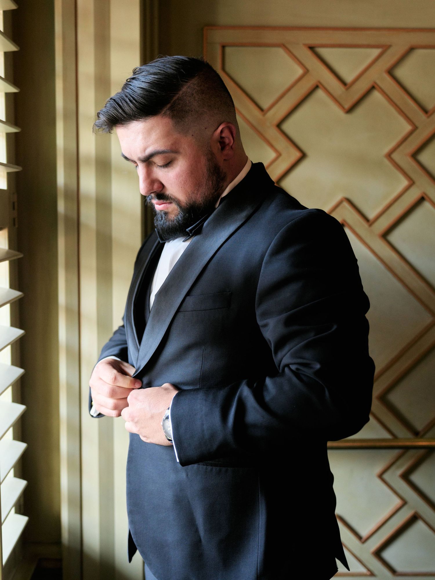 Groom buttoning down his suit before his wedding at the grand bohemian hotel