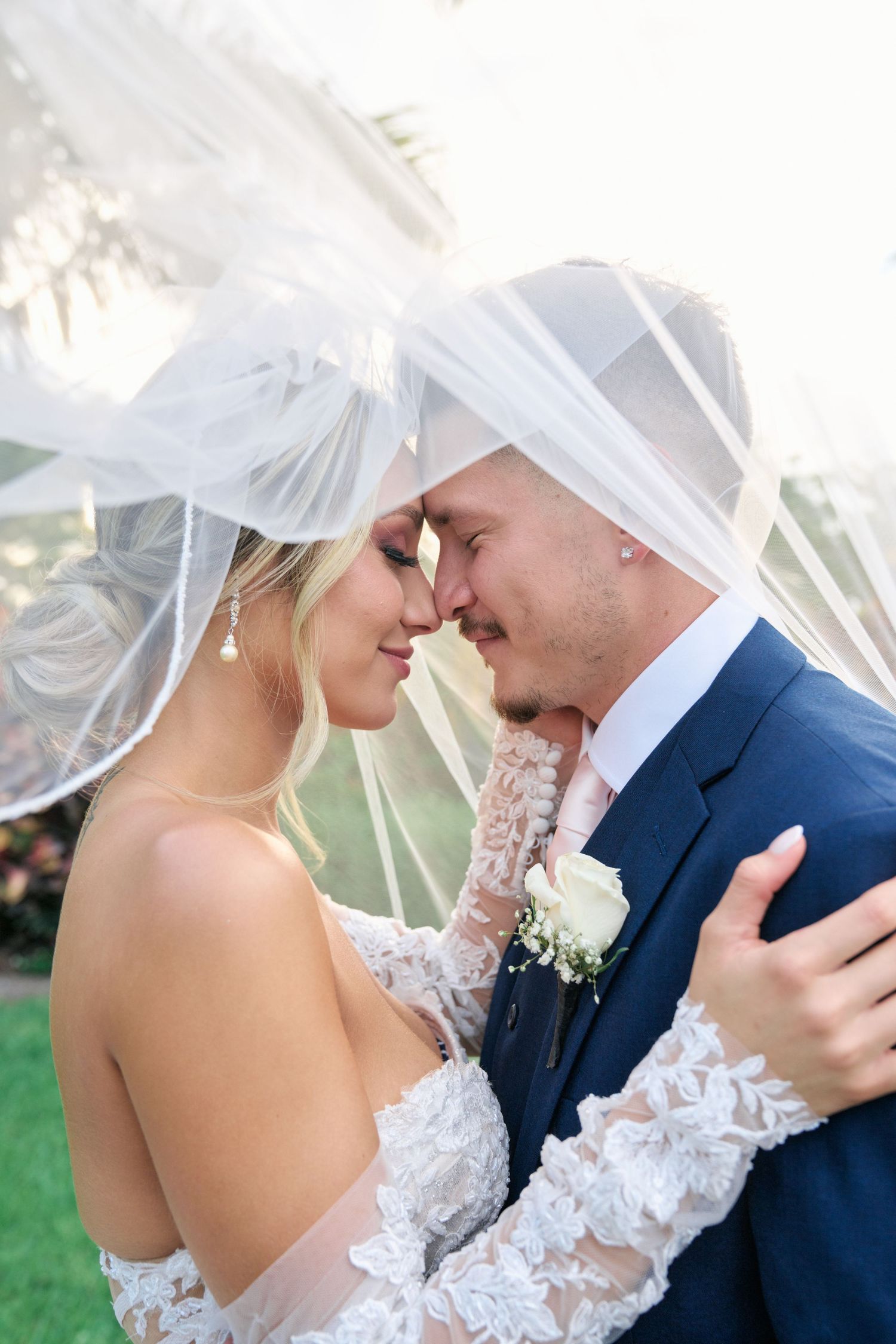 Romantic wedding portrait with flowing veil and delicate lace details against natural lighting.