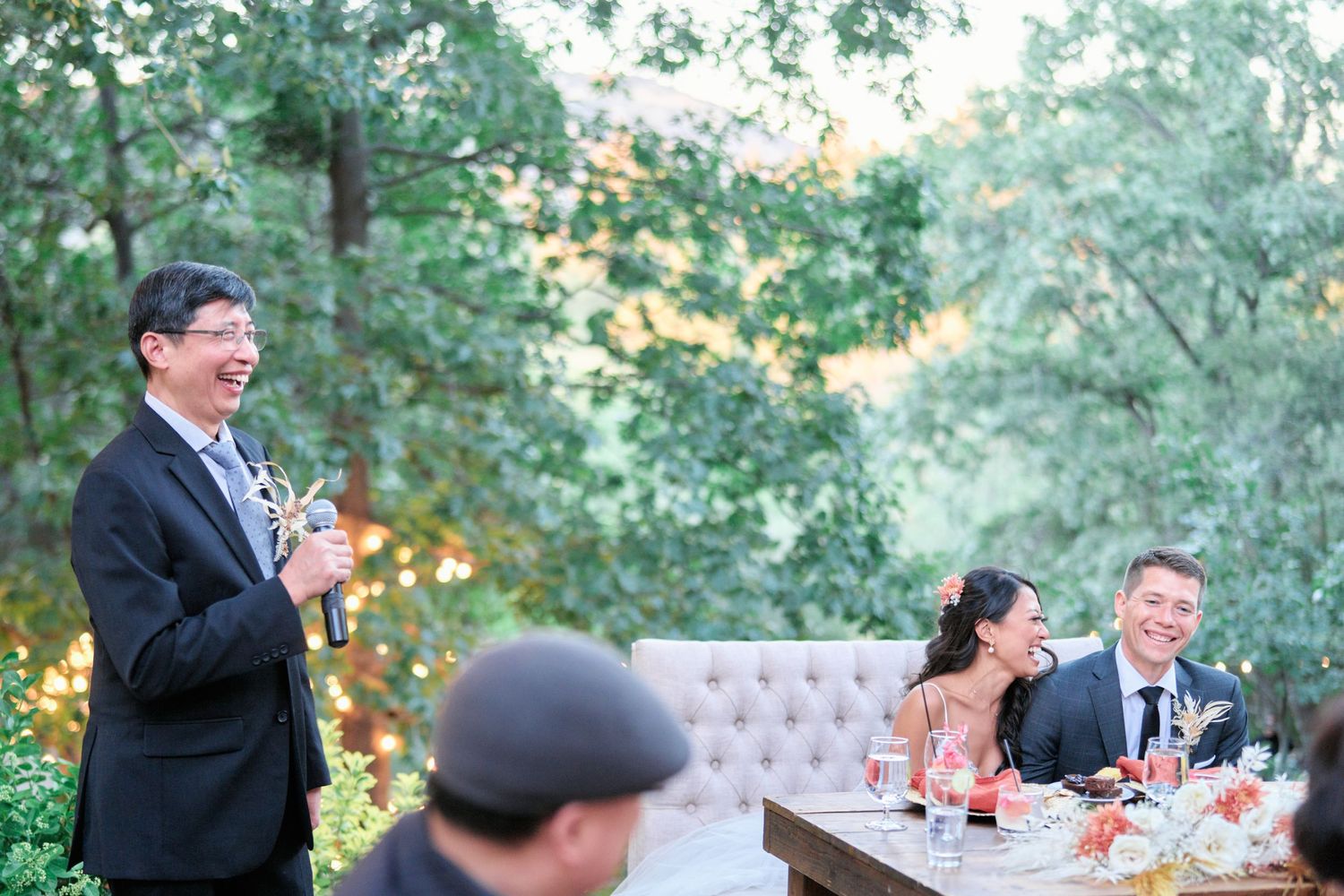 An outdoor wedding reception featuring elegant table settings and string lights.