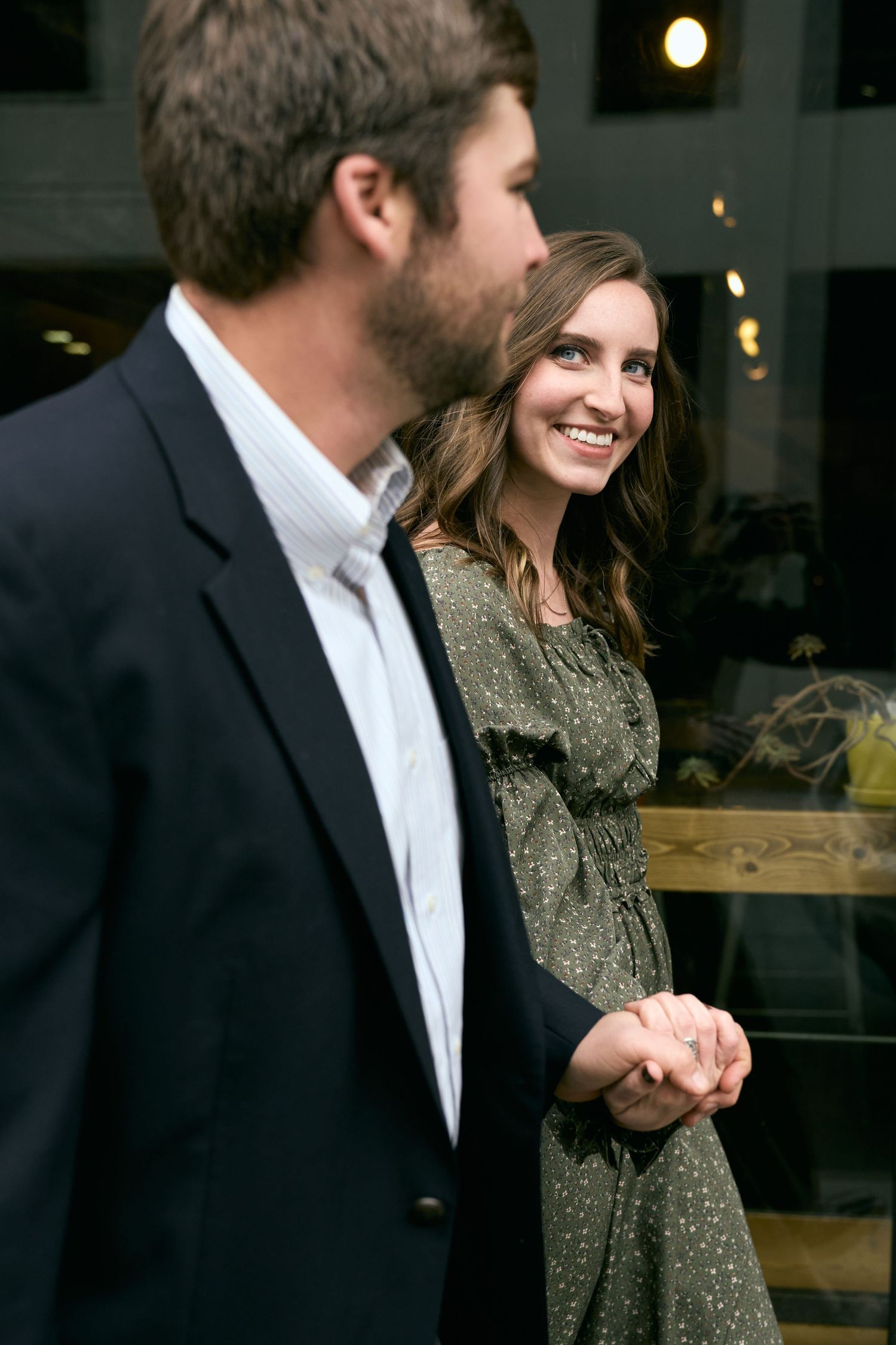 A couple shares an intimate moment while dressed formally outside an urban building.