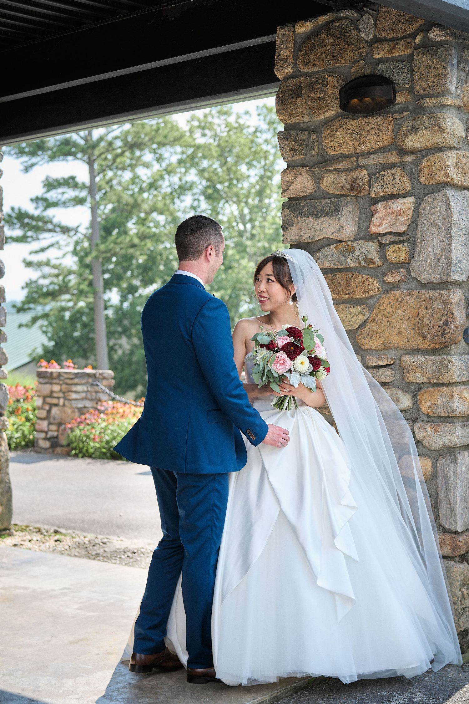 A couple shares an intimate moment under a stone archway during their wedding ceremony.