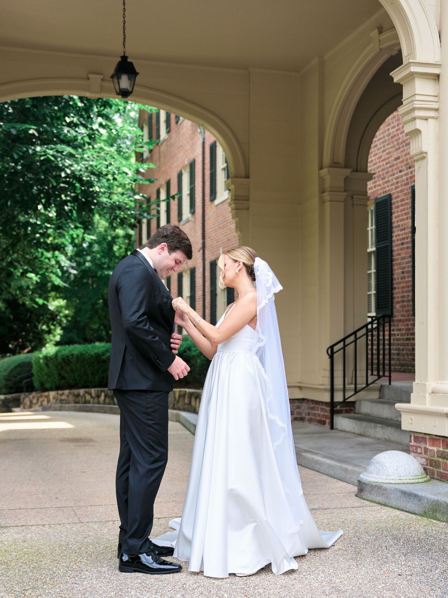 A touching moment between newlyweds as they hold hands under an arched portico.