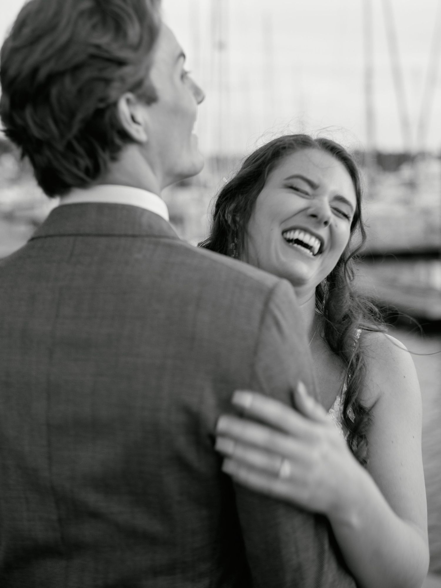 A joyful black and white candid moment captures a couple laughing together in an intimate embrace.
