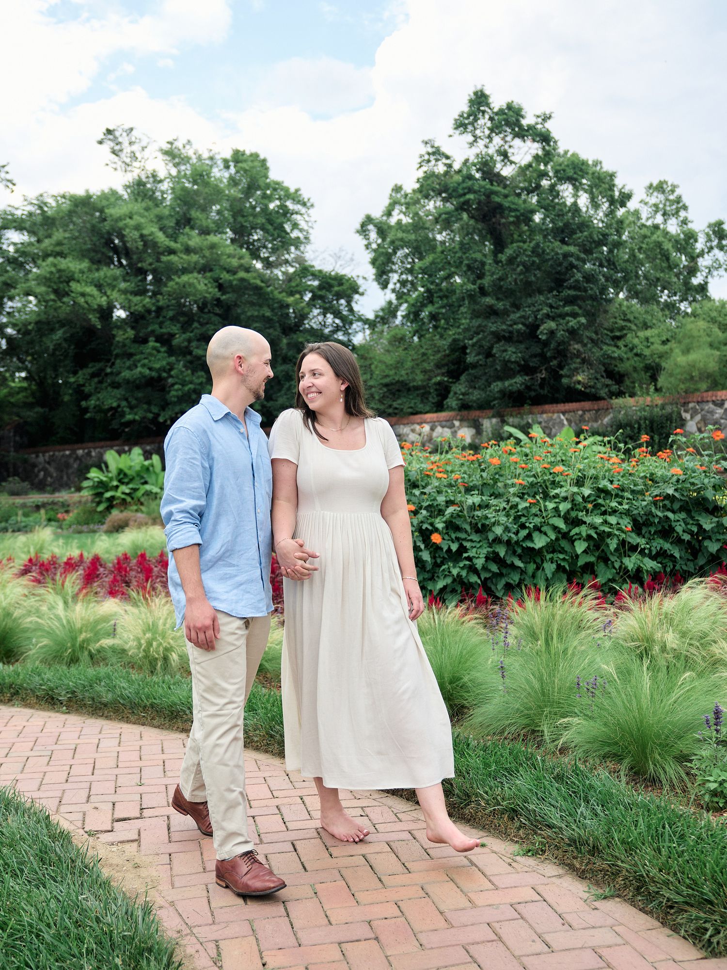 Couple strolls together through landscaped garden with brick pathways.