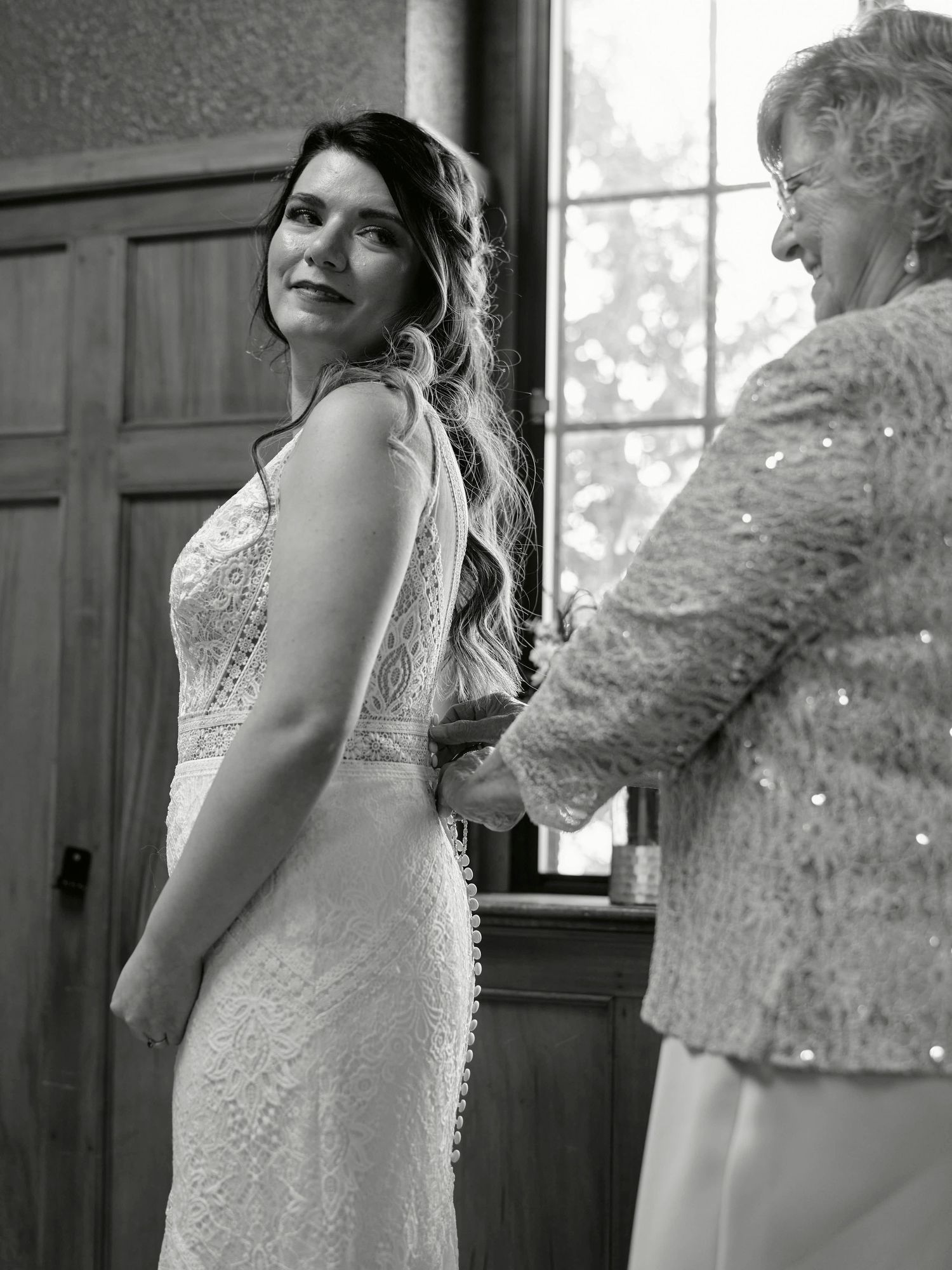 A woman in a lace wedding dress getting final adjustments.