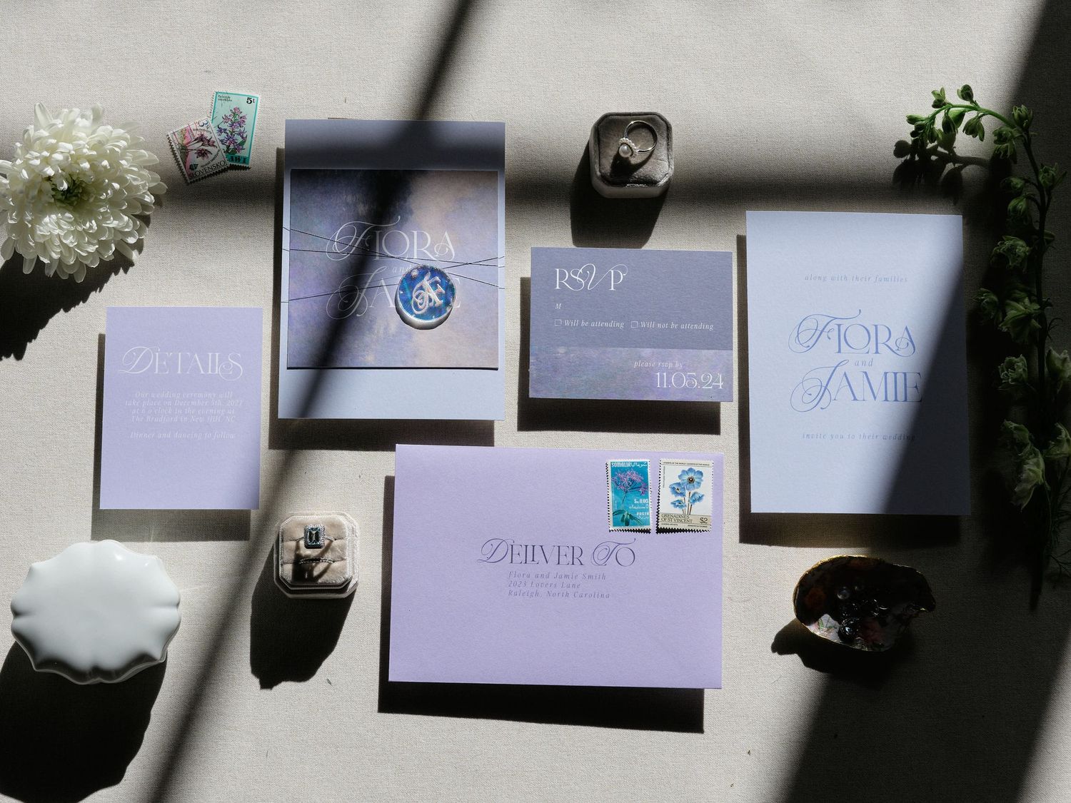 Details of wedding invitations and rings next to a window with shadows.