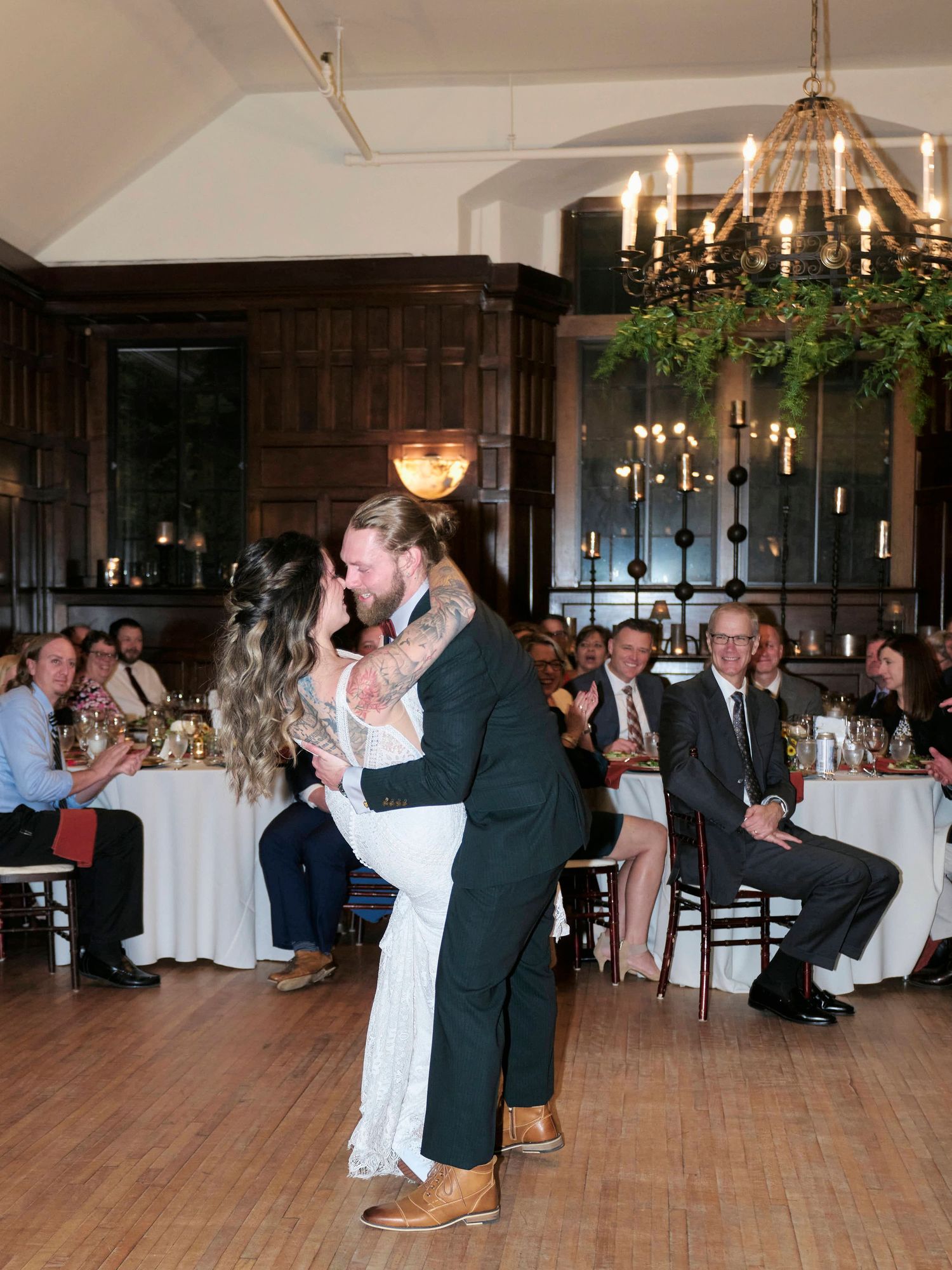 Wedding celebration first dance in an elegant wood-paneled reception hall.