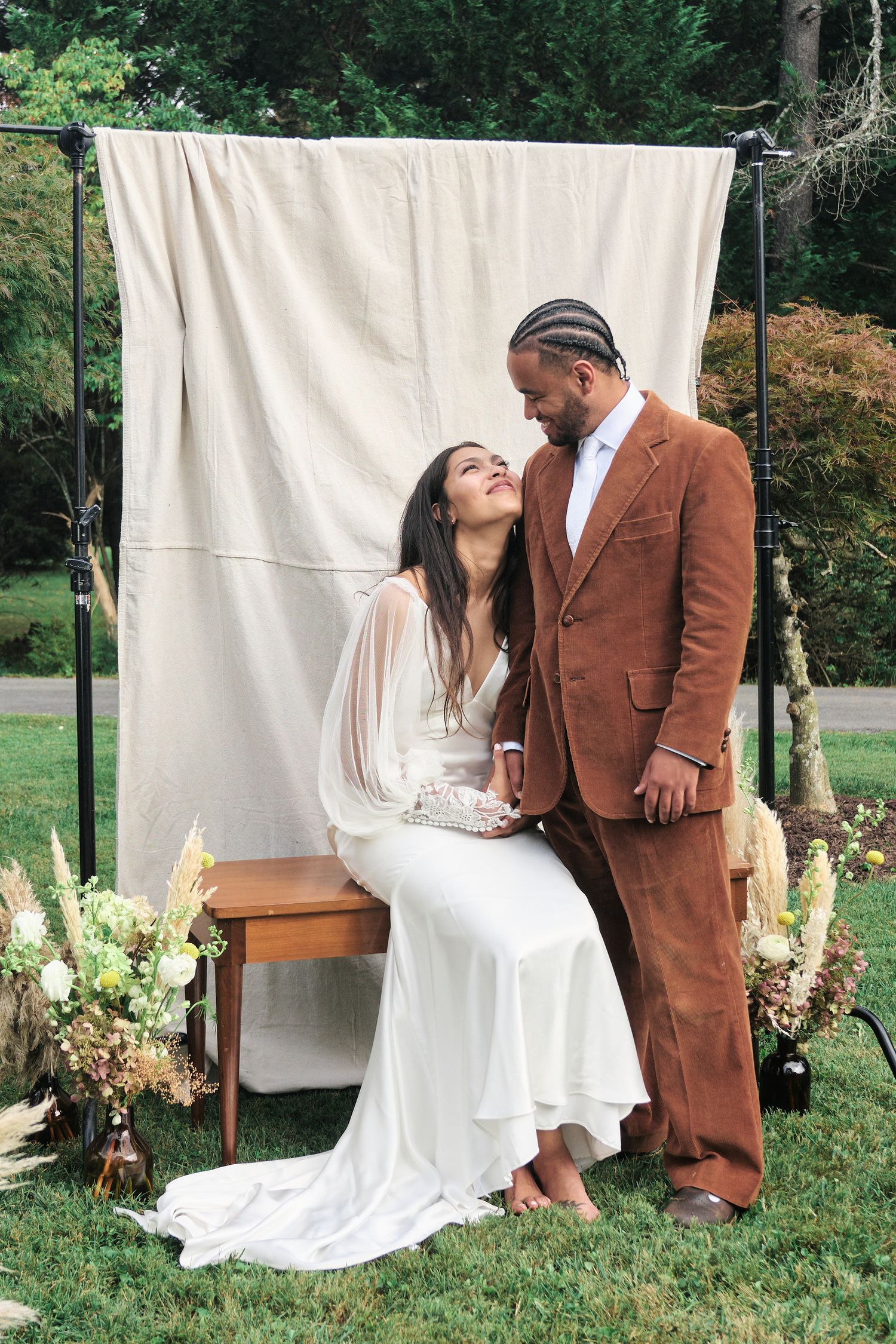 Romantic wedding portrait of couple sharing tender moment against white backdrop outdoors.