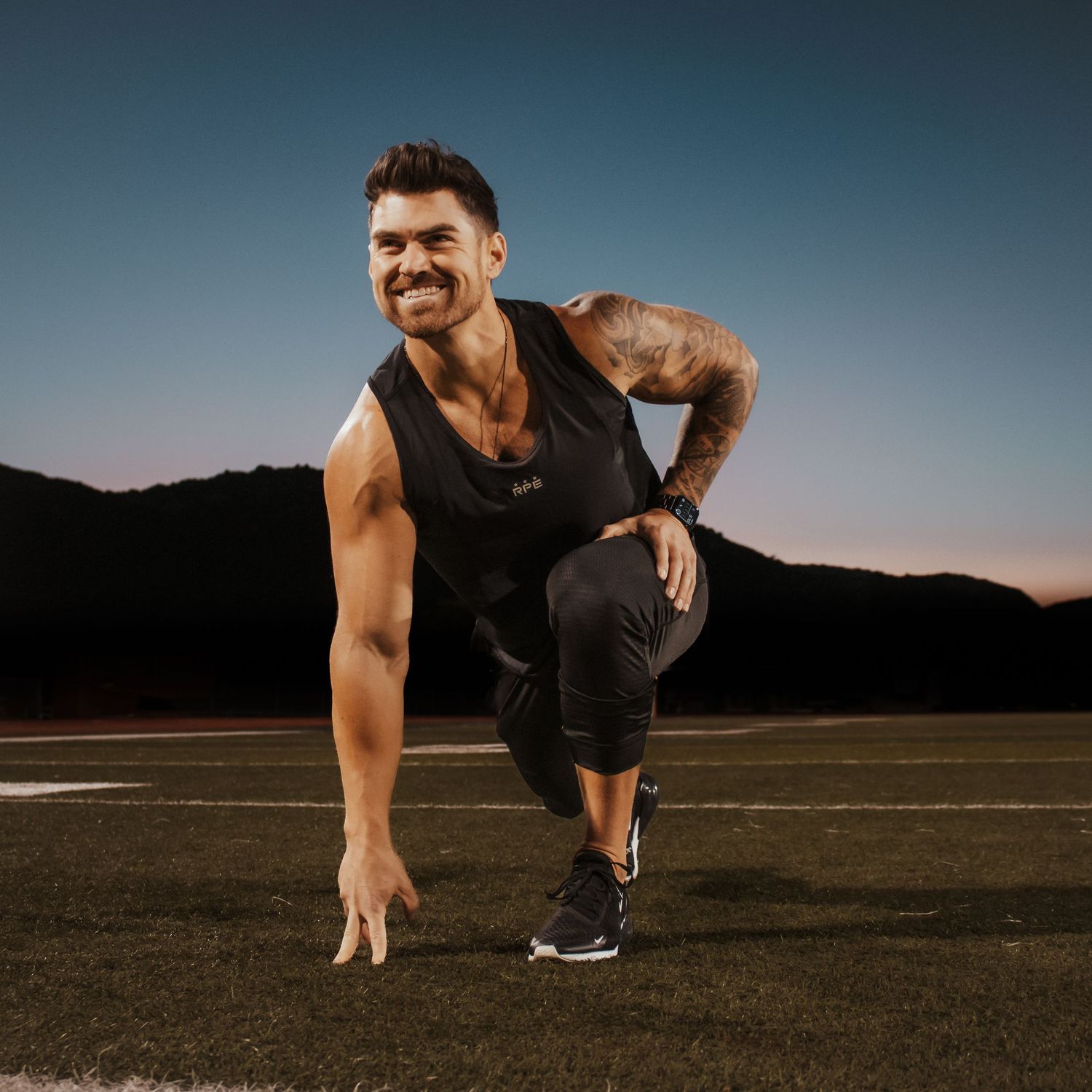 Athletic person performing dynamic jumping exercises outdoors during sunset.