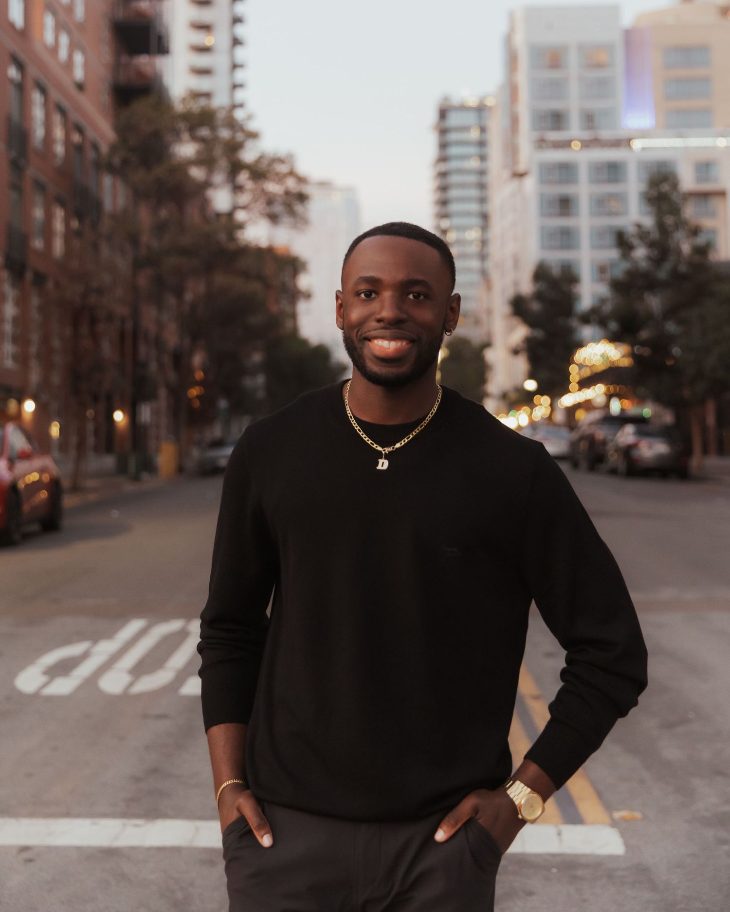 Professional outdoor portrait session featuring a person in a black sweater against an urban backdrop with tall buildings.