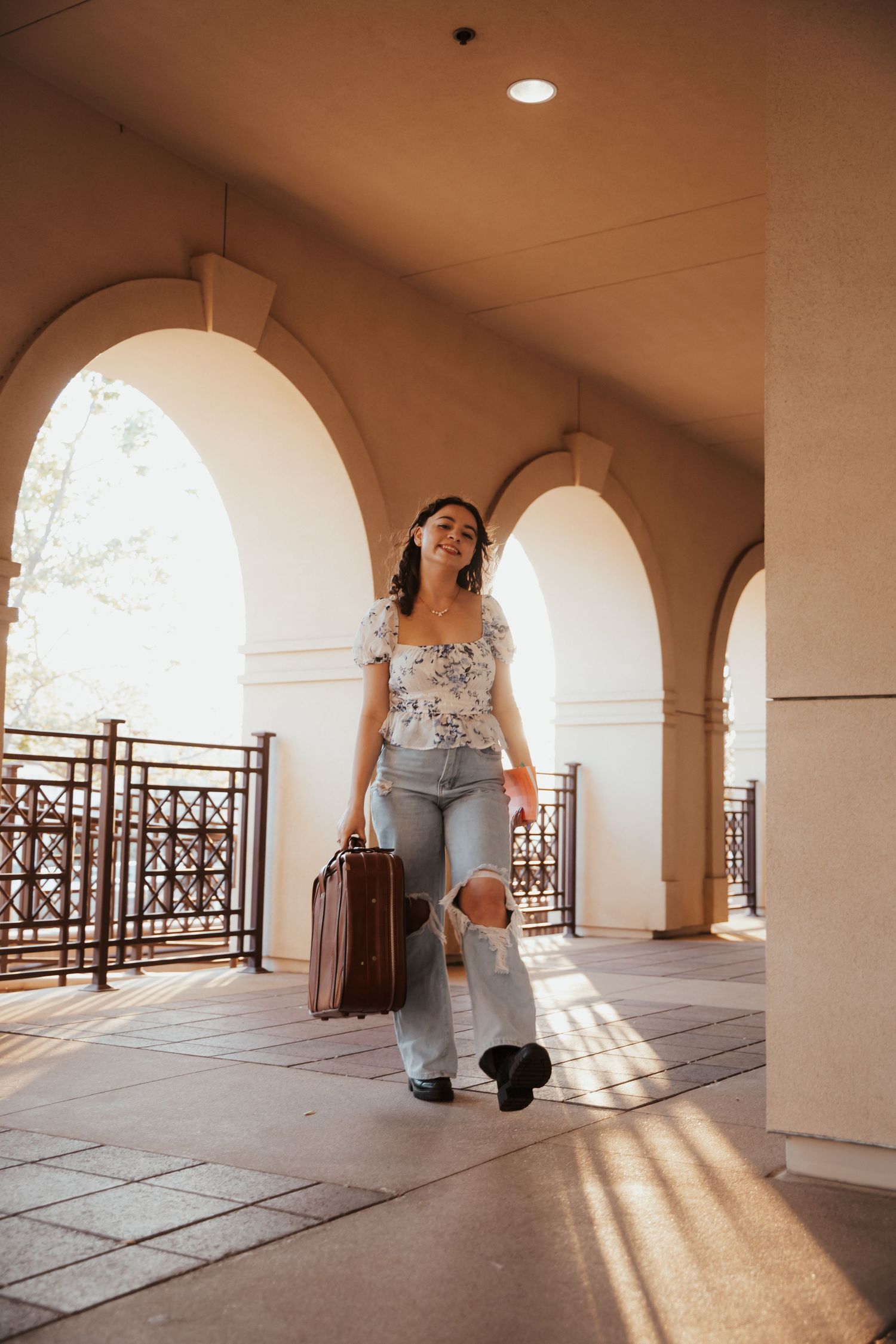 A sunlit colonnade with arched walkways and decorative railings creates dramatic shadows.
